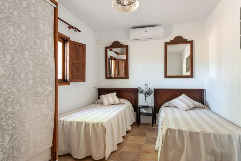 Un dormitorio con dos camas, una ventana y espejos en la pared.