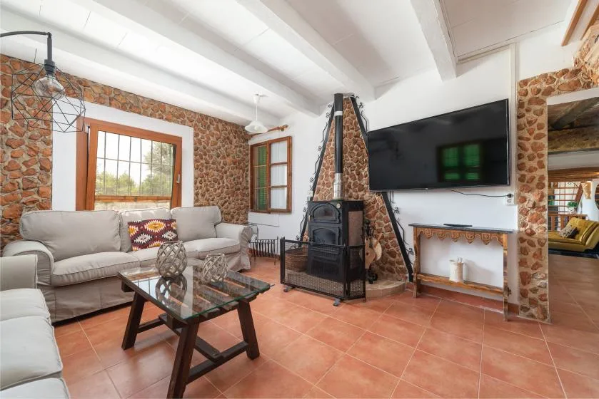 Una sala de estar con asientos, una mesa de centro de vidrio y un televisor sobre la chimenea.