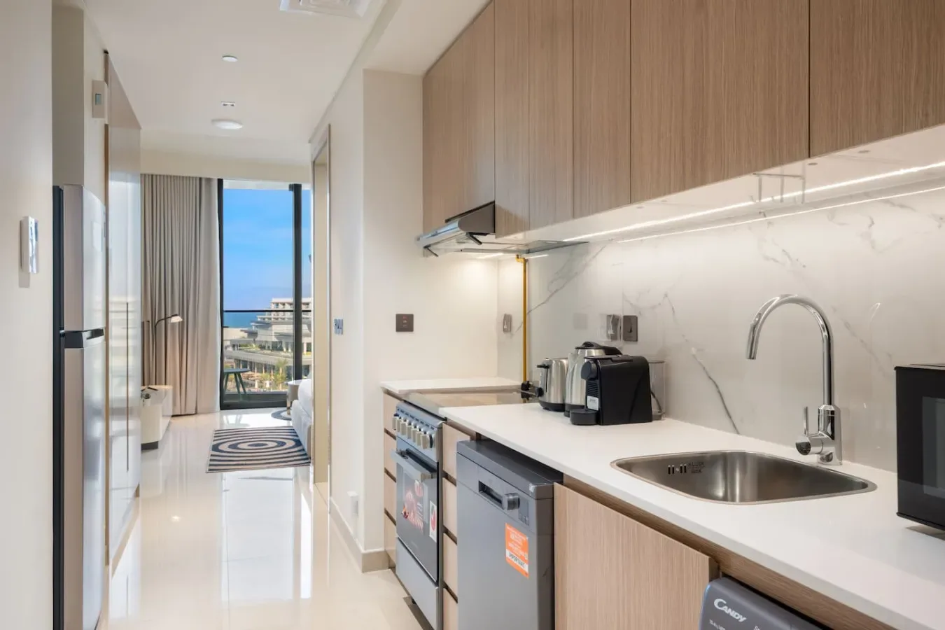Una cocina moderna con una encimera larga y un balcón visible a través de la puerta.