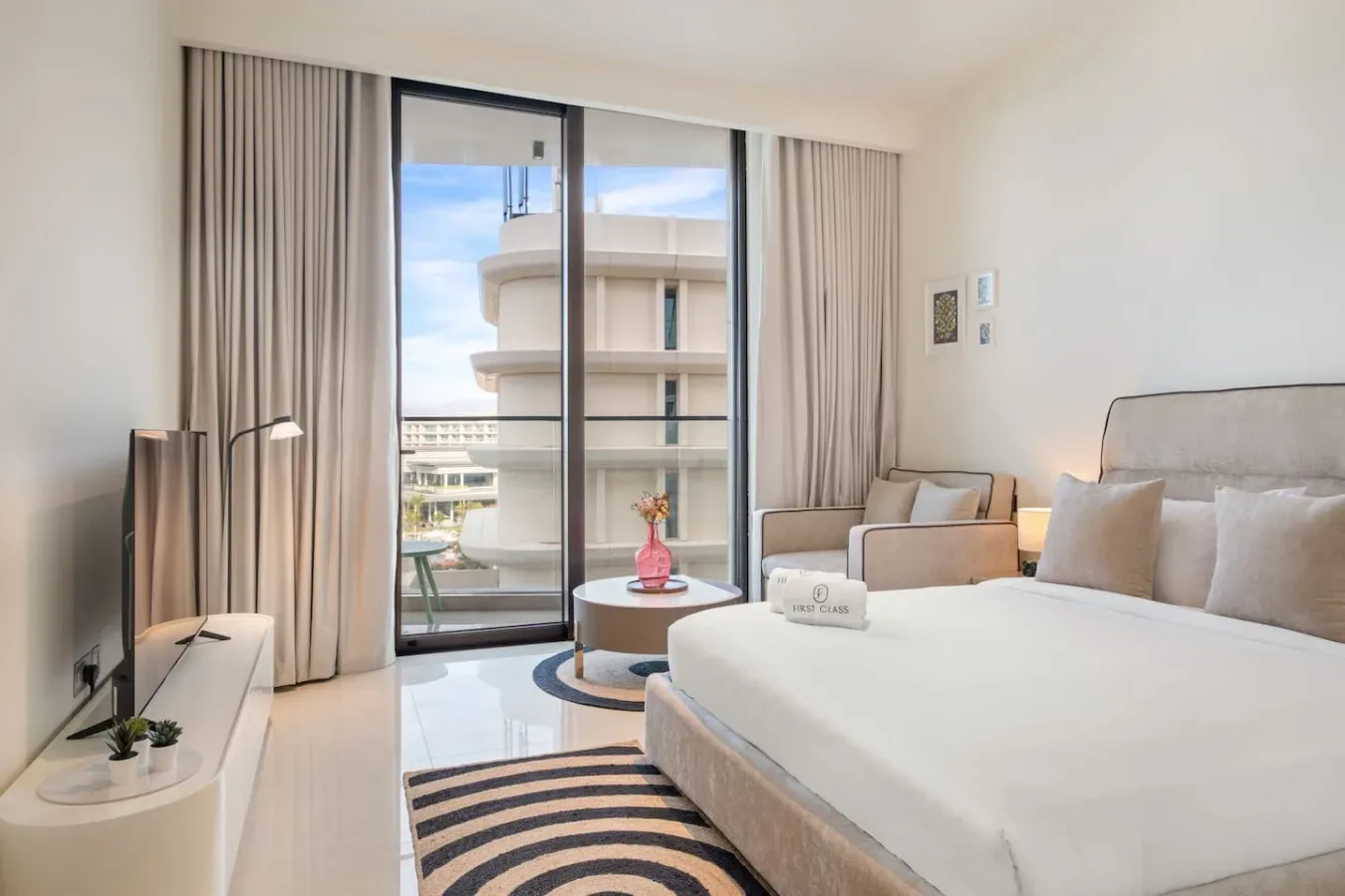Un dormitorio luminoso con una cama grande, zona de estar y puertas correderas de cristal.