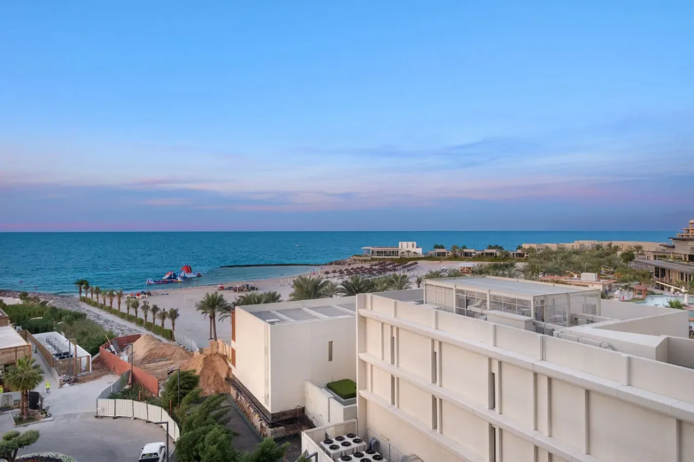 Un complejo costero domina el mar, con edificios junto a la playa y barcos en la costa.