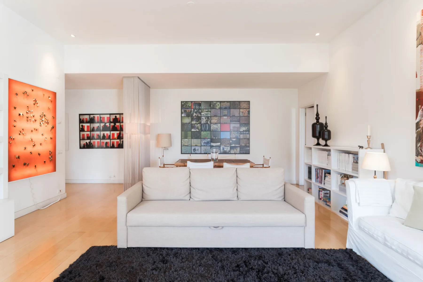 A bright living room with seating, wall art, and a bookcase.