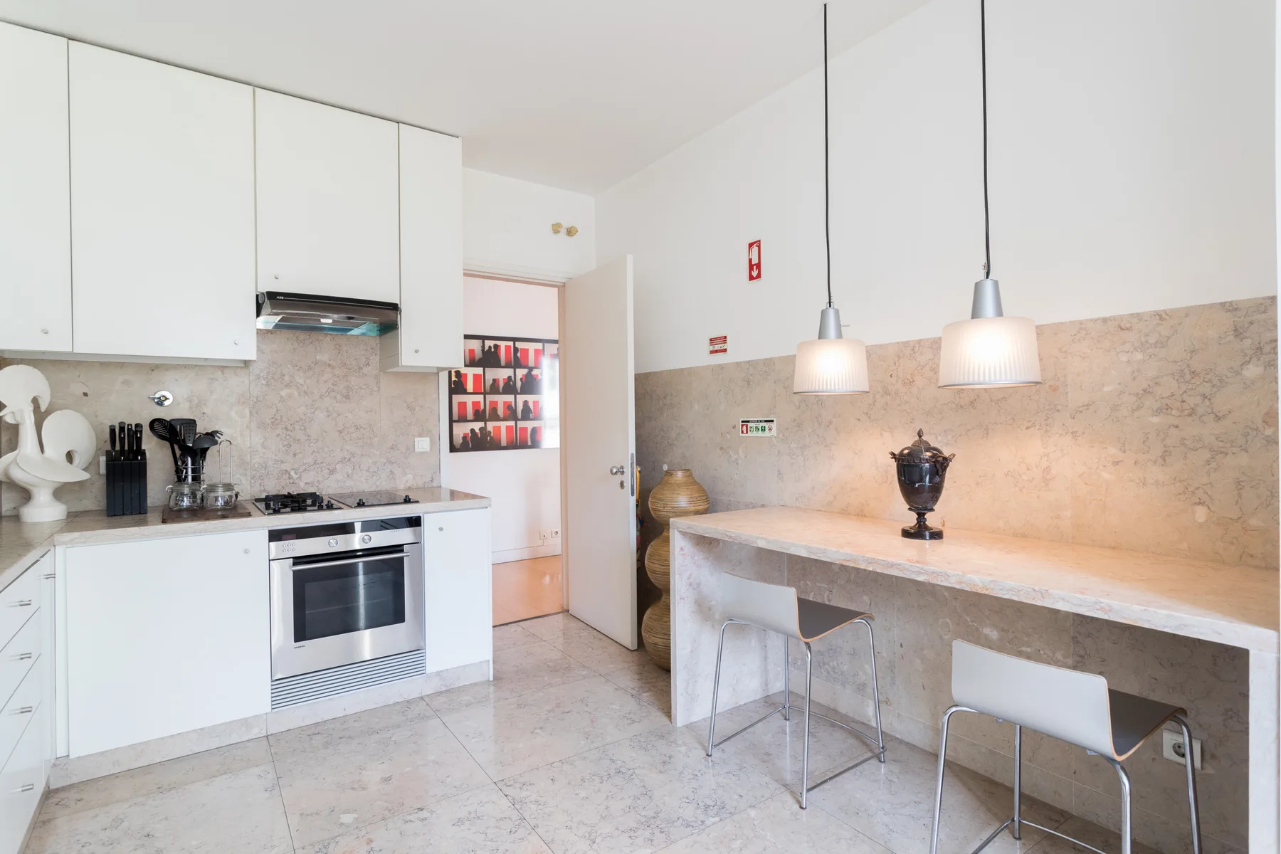 A bright kitchen with white cabinets and a stone-topped counter with seating.