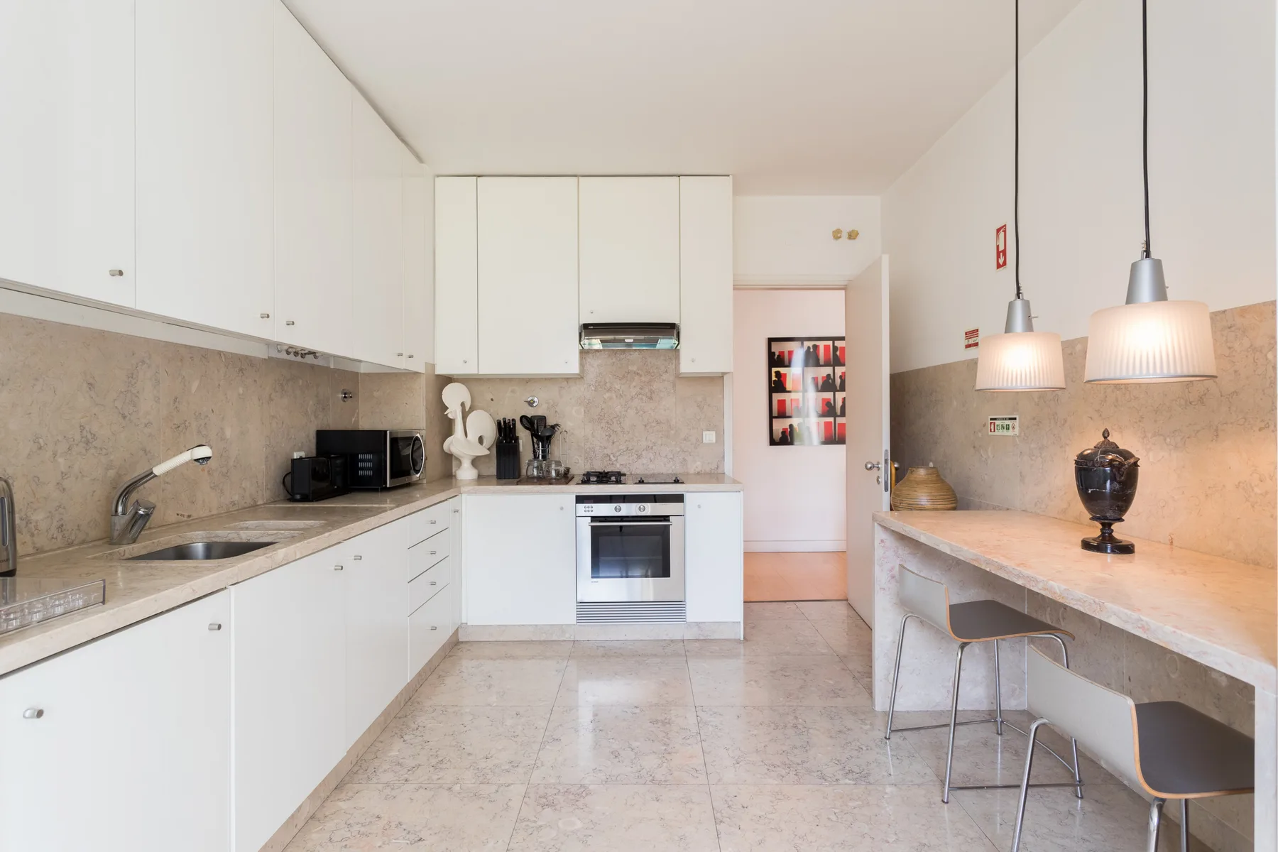 A bright kitchen with white cabinets, a countertop, and pendant lights.