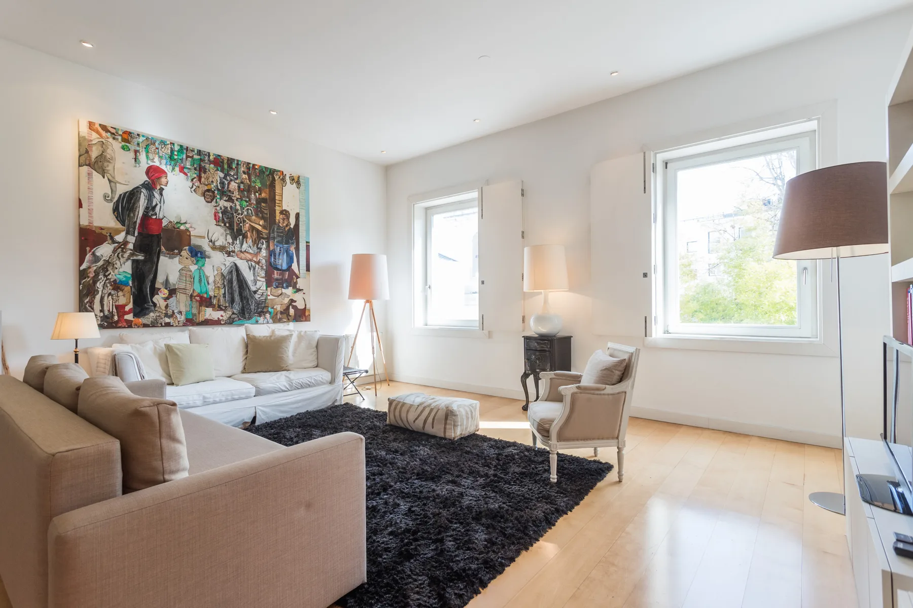 A bright living room with seating arranged around a dark rug.