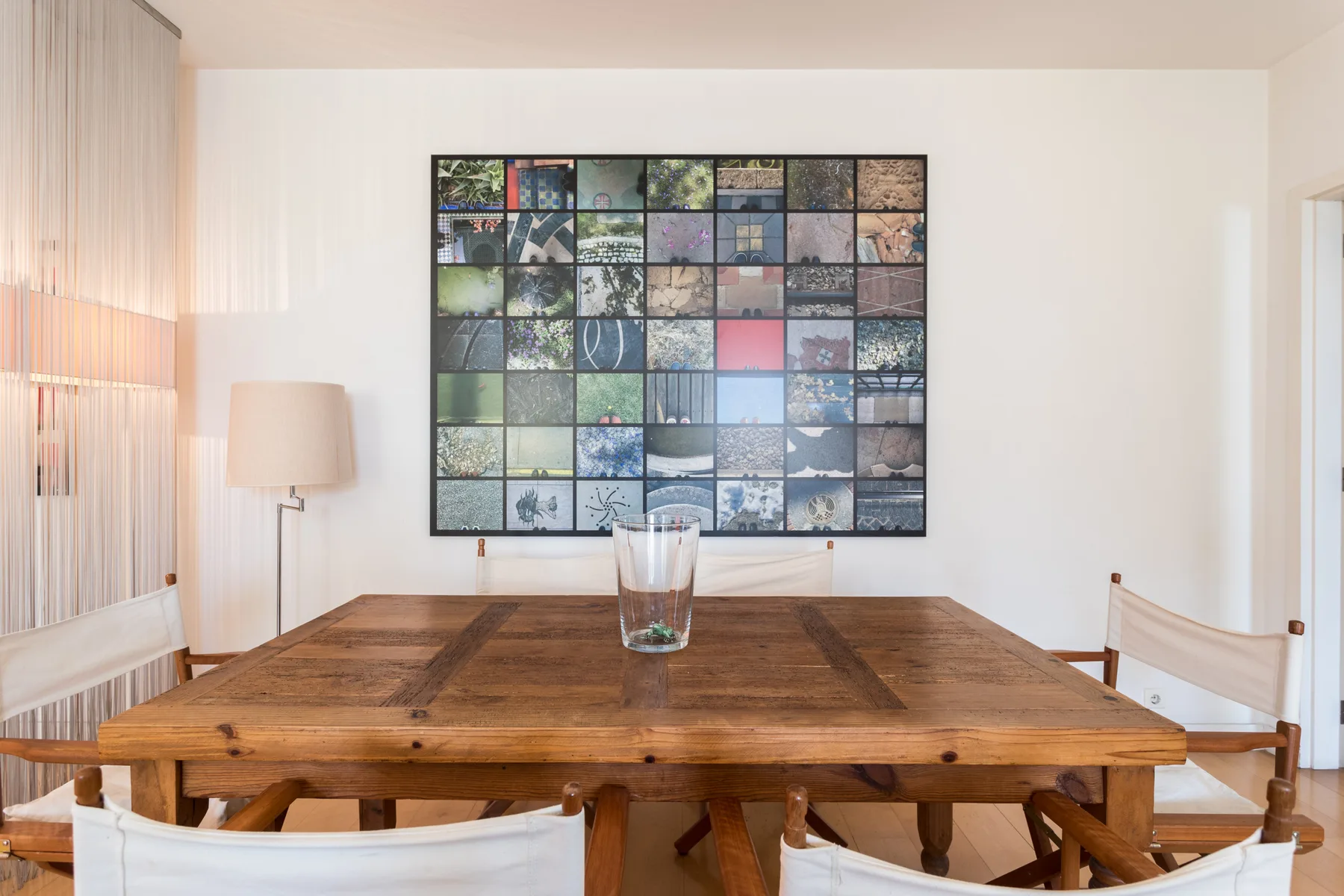 A dining area with a wooden table and a framed collage on the wall.