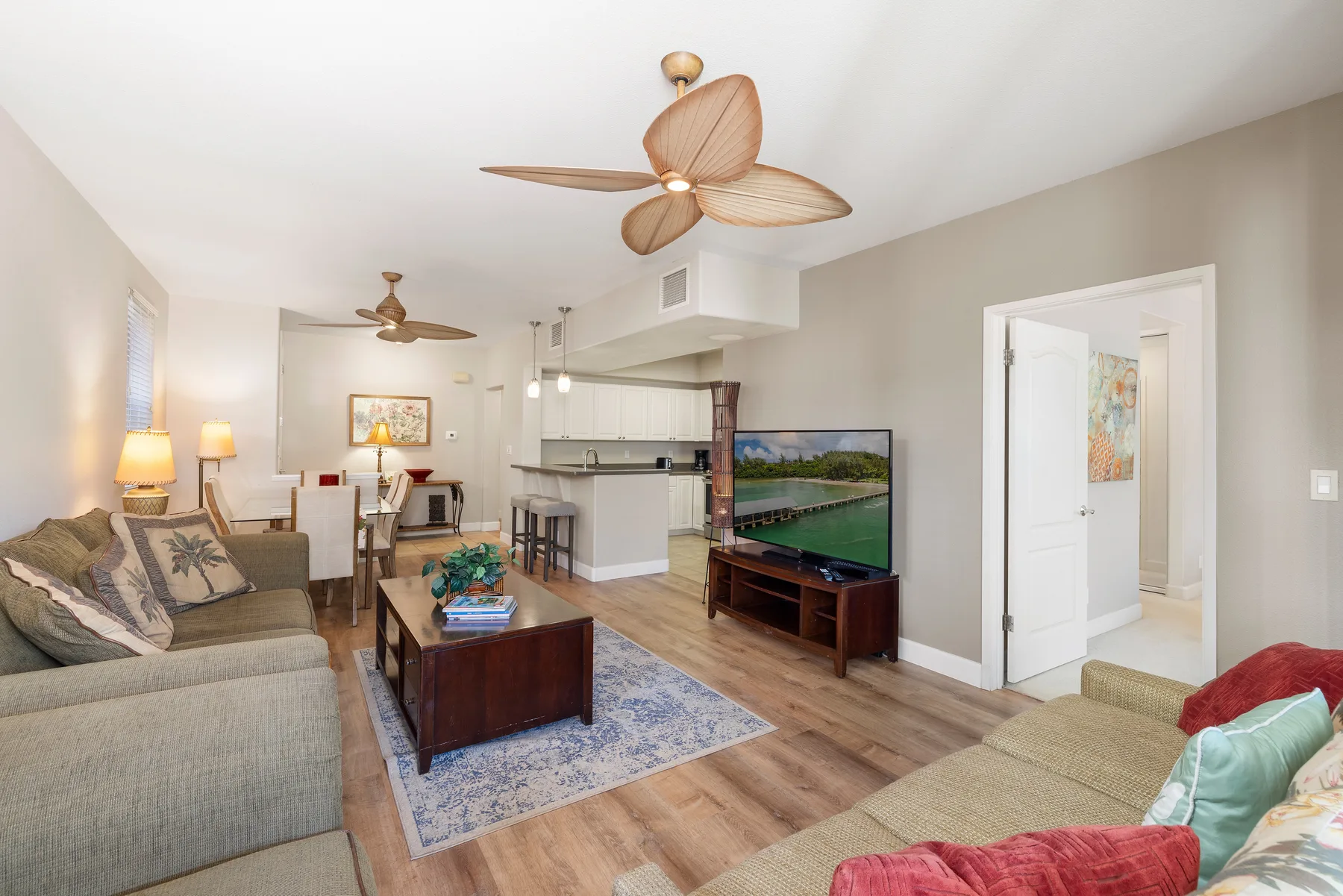 A living room with seating, a coffee table, and an open kitchen.
