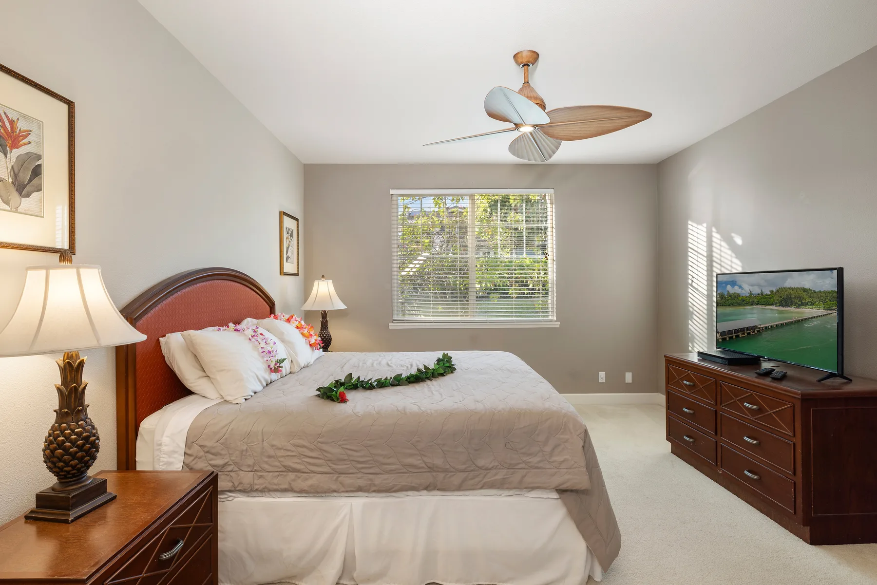 A bedroom with a neatly made bed and a television on a dresser.