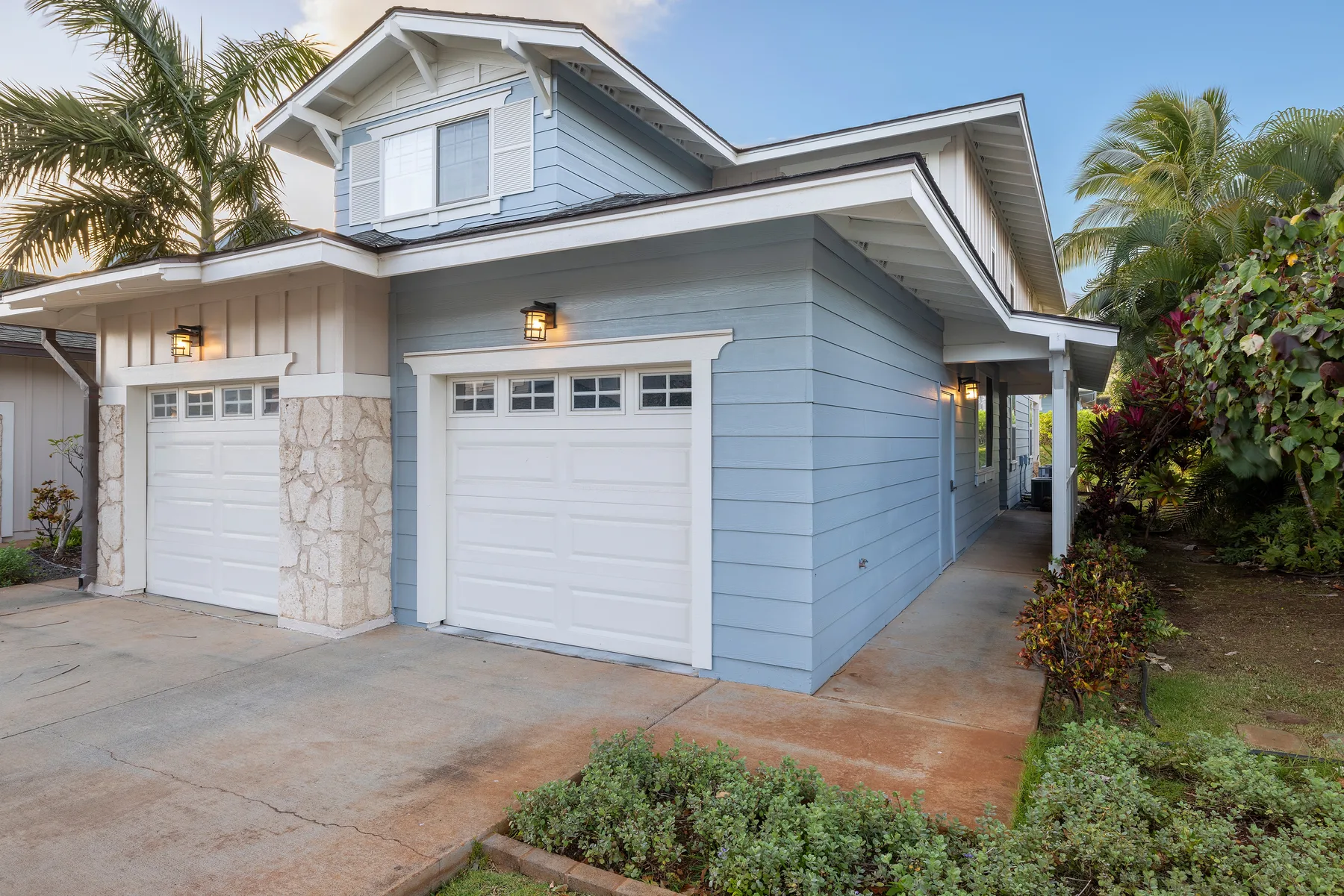 A blue house exterior with two garage doors and a driveway.