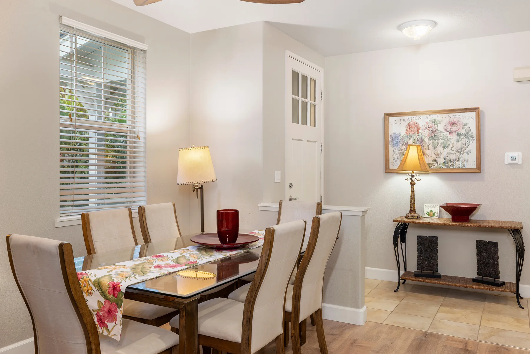 A dining room with a table, chairs, and a framed floral picture on the wall.