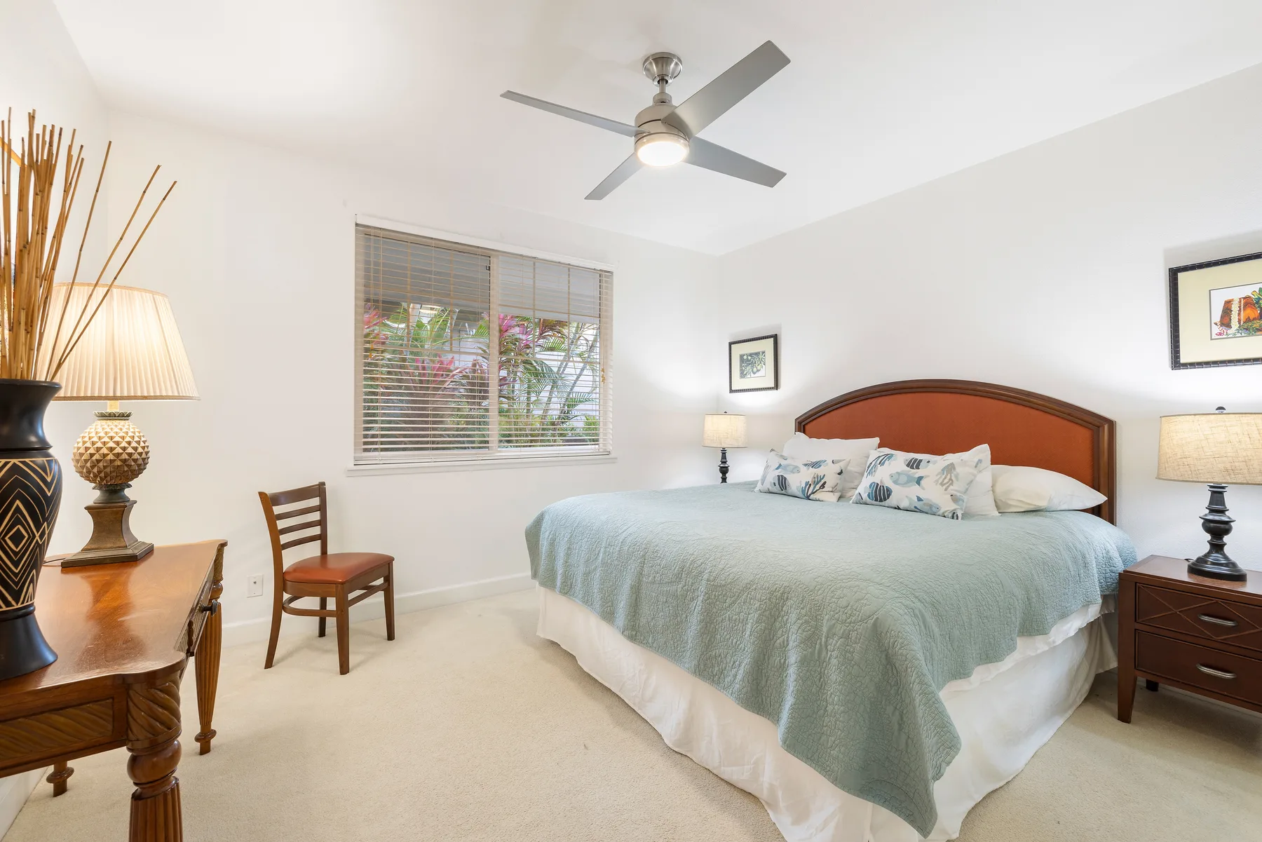 A bright bedroom with a large bed, wooden headboard, and window.