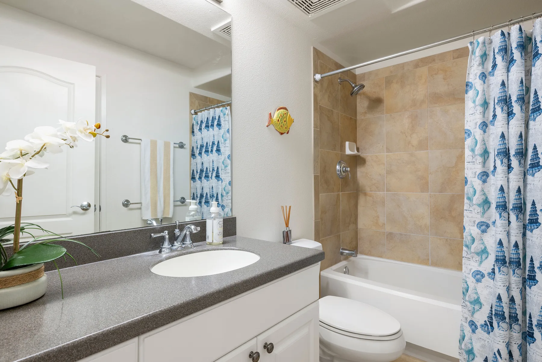 A bathroom with a sink vanity and a bathtub behind a patterned shower curtain.