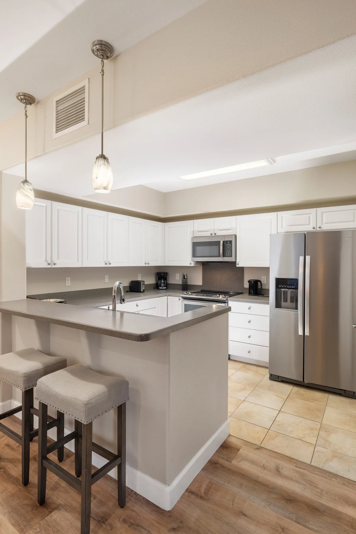 A bright kitchen with white cabinets, a central counter, and stainless steel appliances.