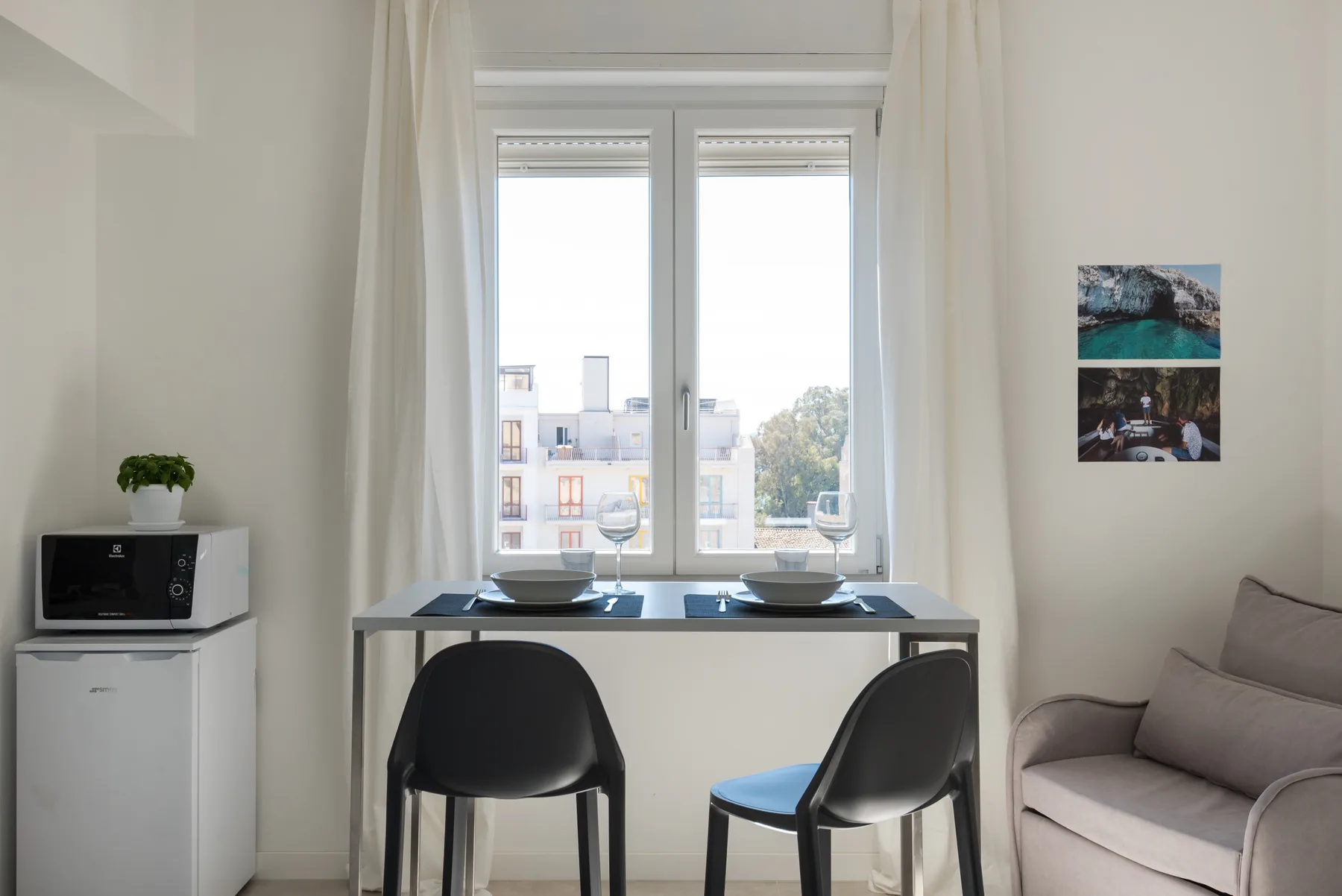 Una zona de comedor junto a una ventana luminosa tiene una mesa pequeña y asientos.