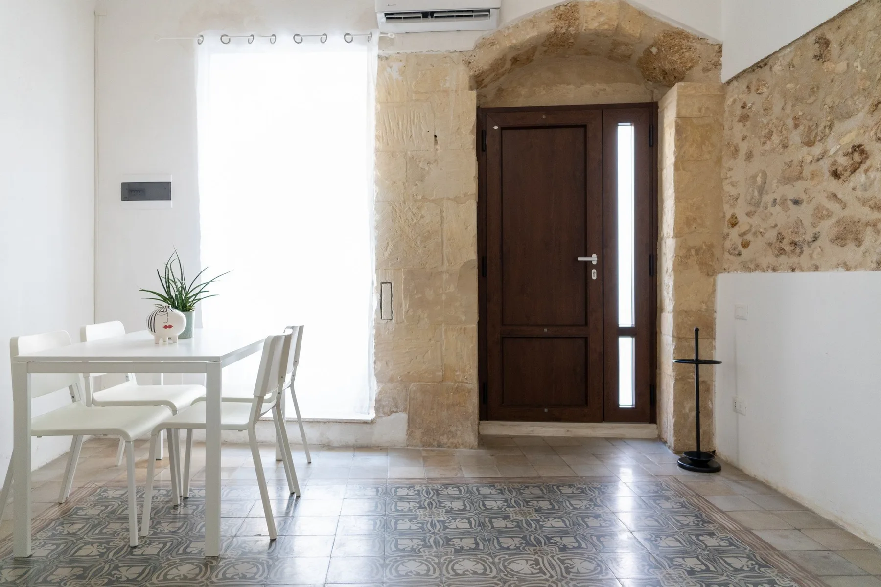 A bright entryway with a dark wooden door and a small dining table.