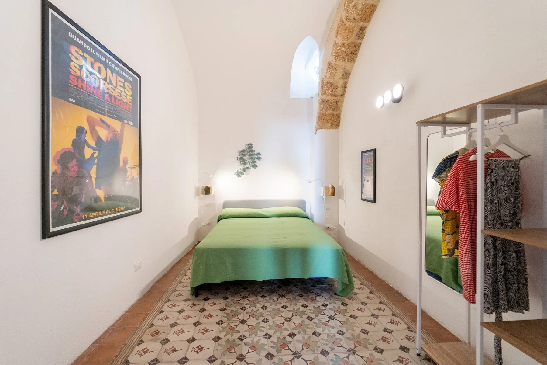 A bedroom with a green bed beneath a high arched ceiling.