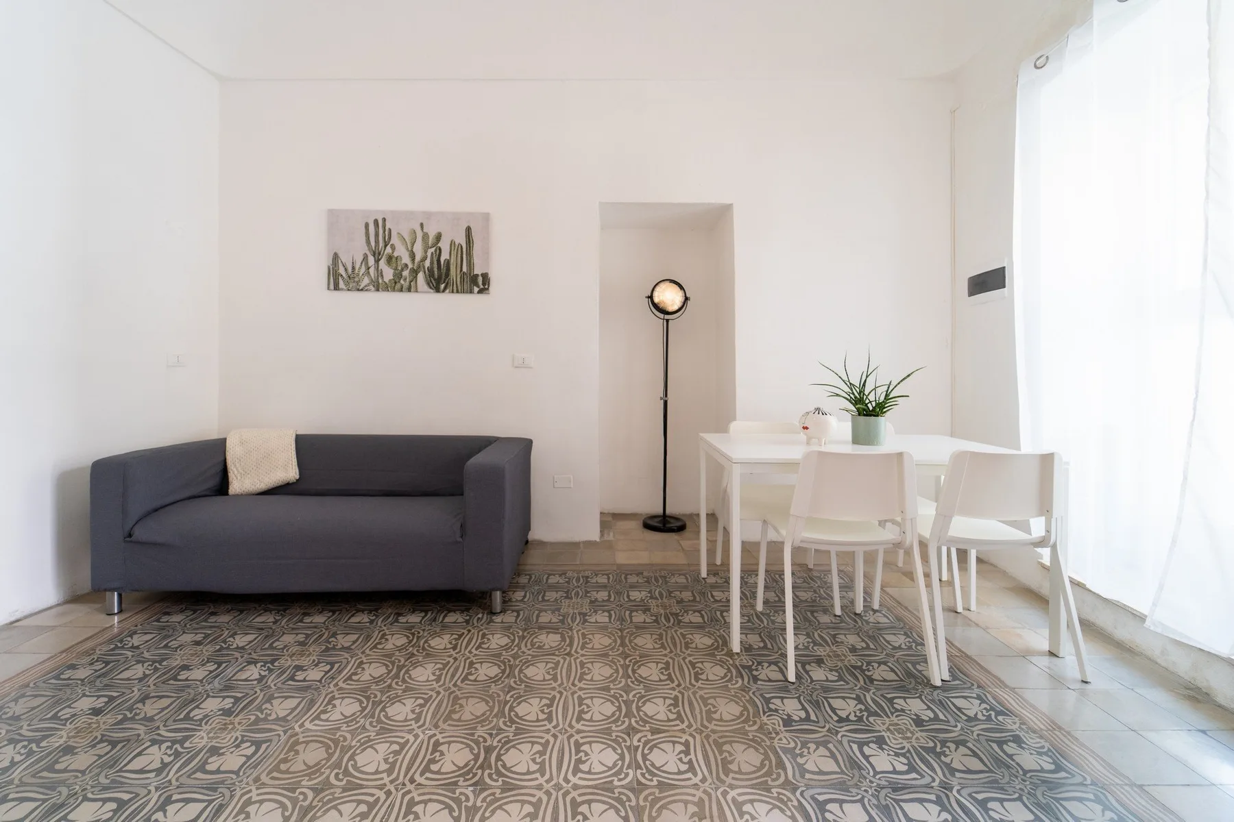 A bright living and dining area with seating, a table, and a tall floor lamp.