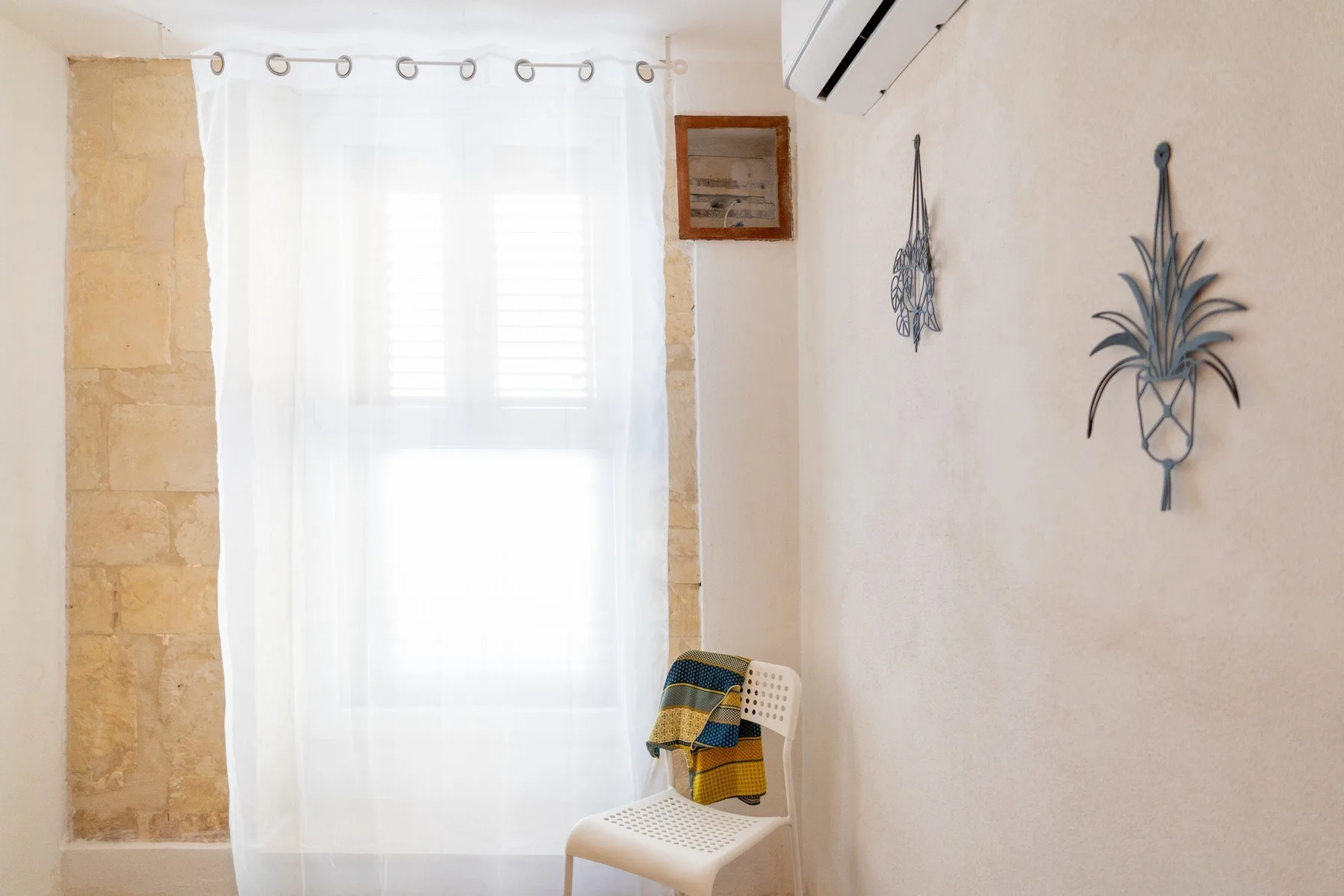 A bright room with a sheer-curtained window and a white chair.
