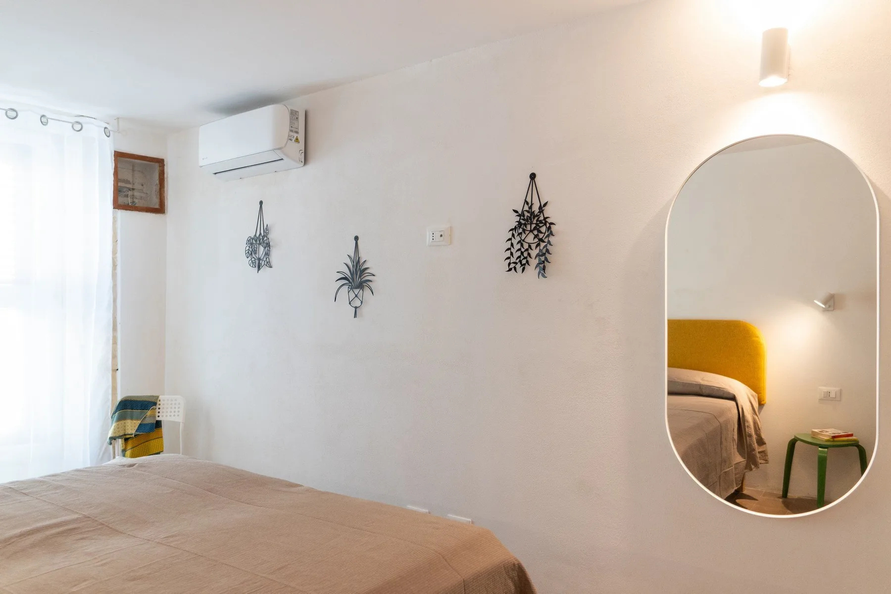 A bedroom with a bed, wall decorations, and an arched mirror.