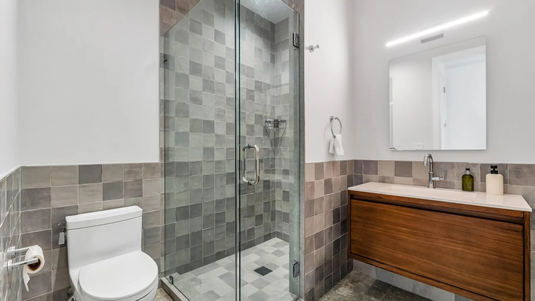 Un baño moderno con una ducha de vidrio y un tocador de madera.