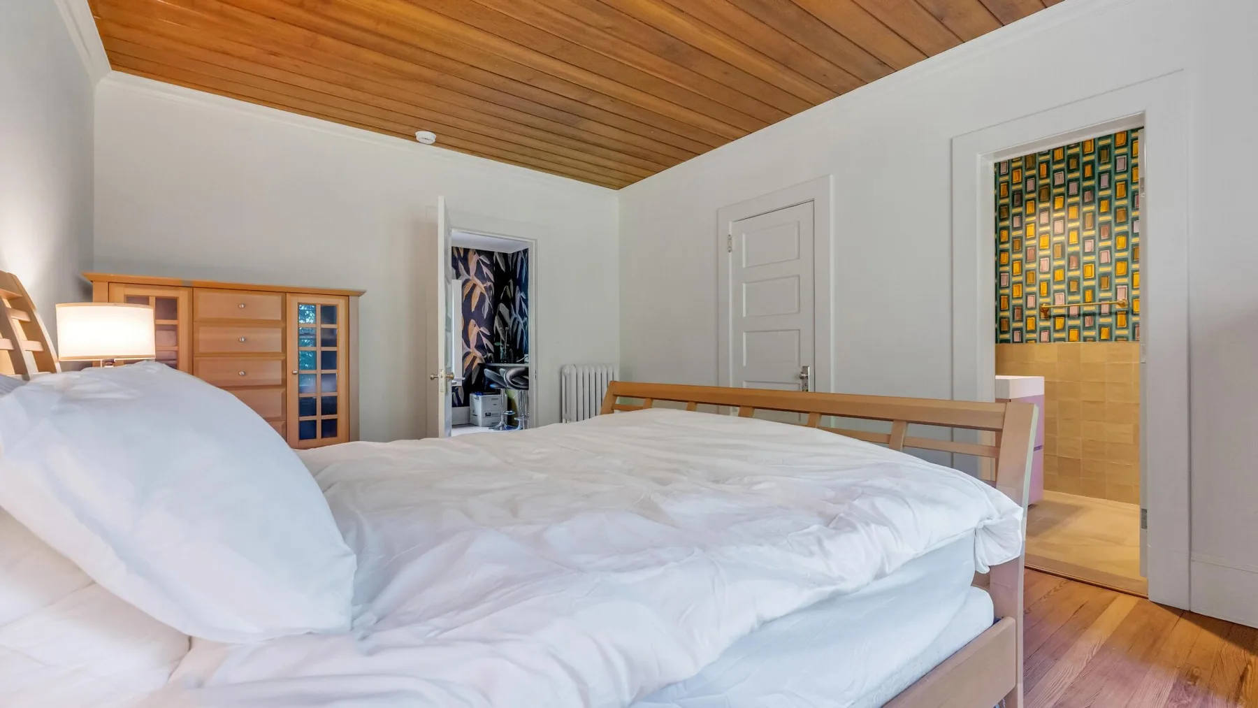 Un dormitorio con una cama bajo un techo revestido de madera.