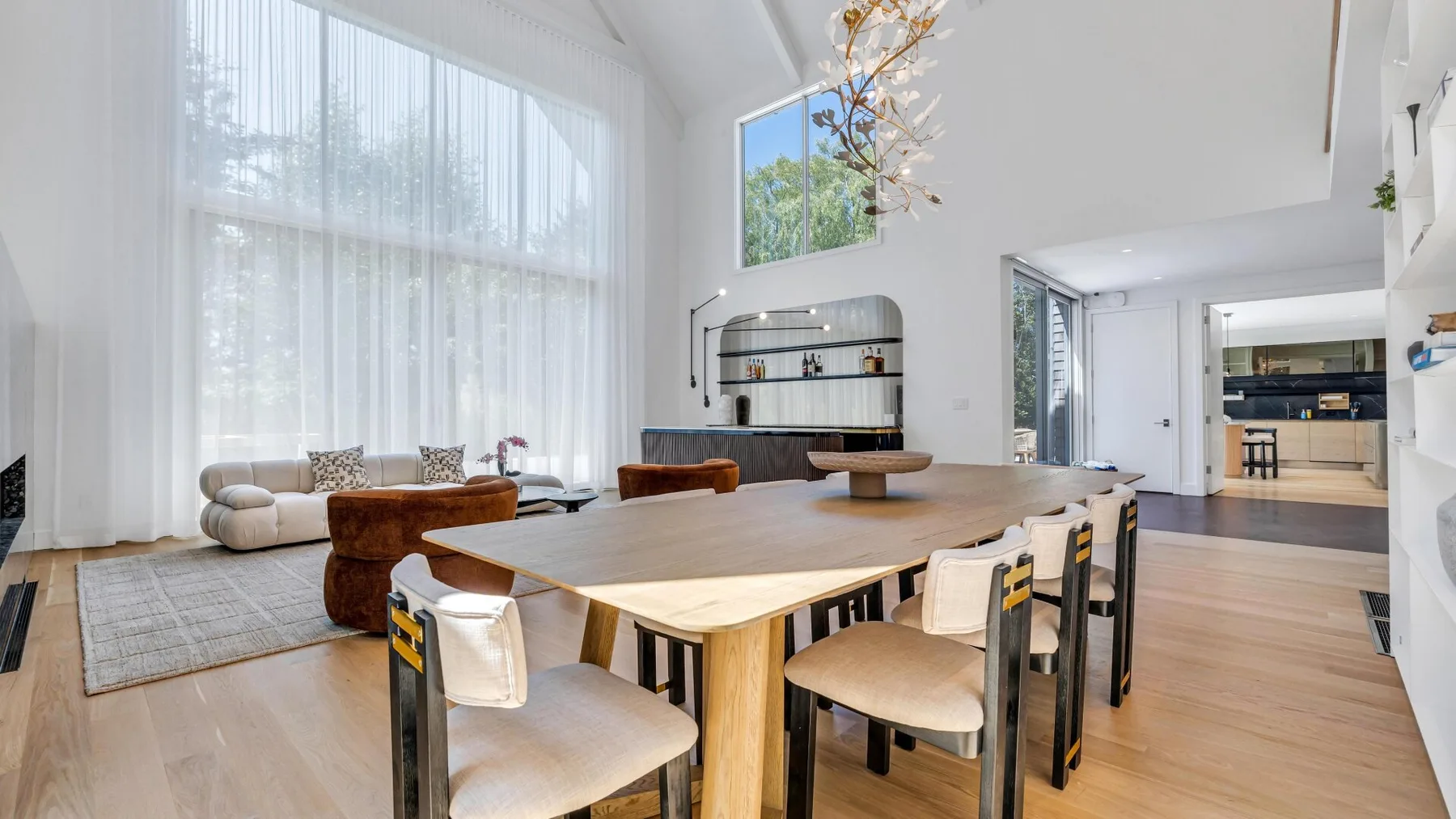 Un comedor luminoso con una larga mesa de madera junto a grandes ventanas.
