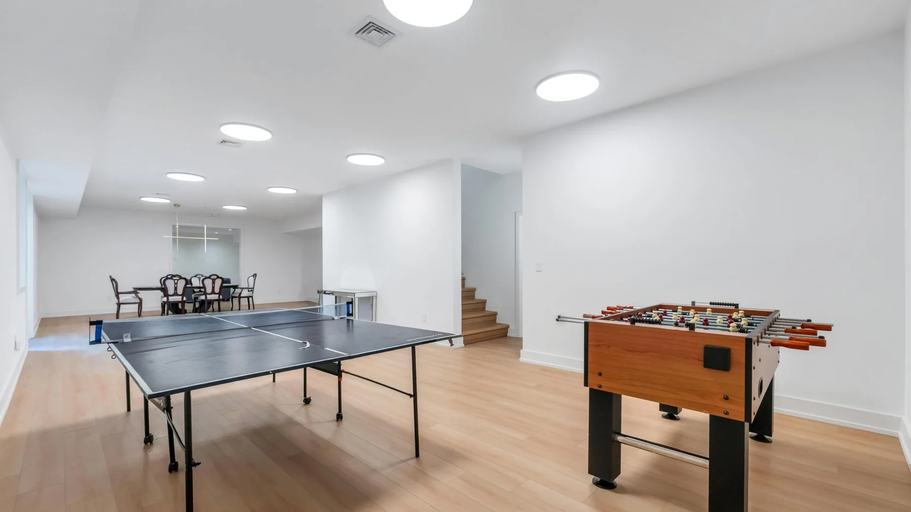 Una luminosa sala de juegos tiene una mesa de ping-pong y una de futbolín.