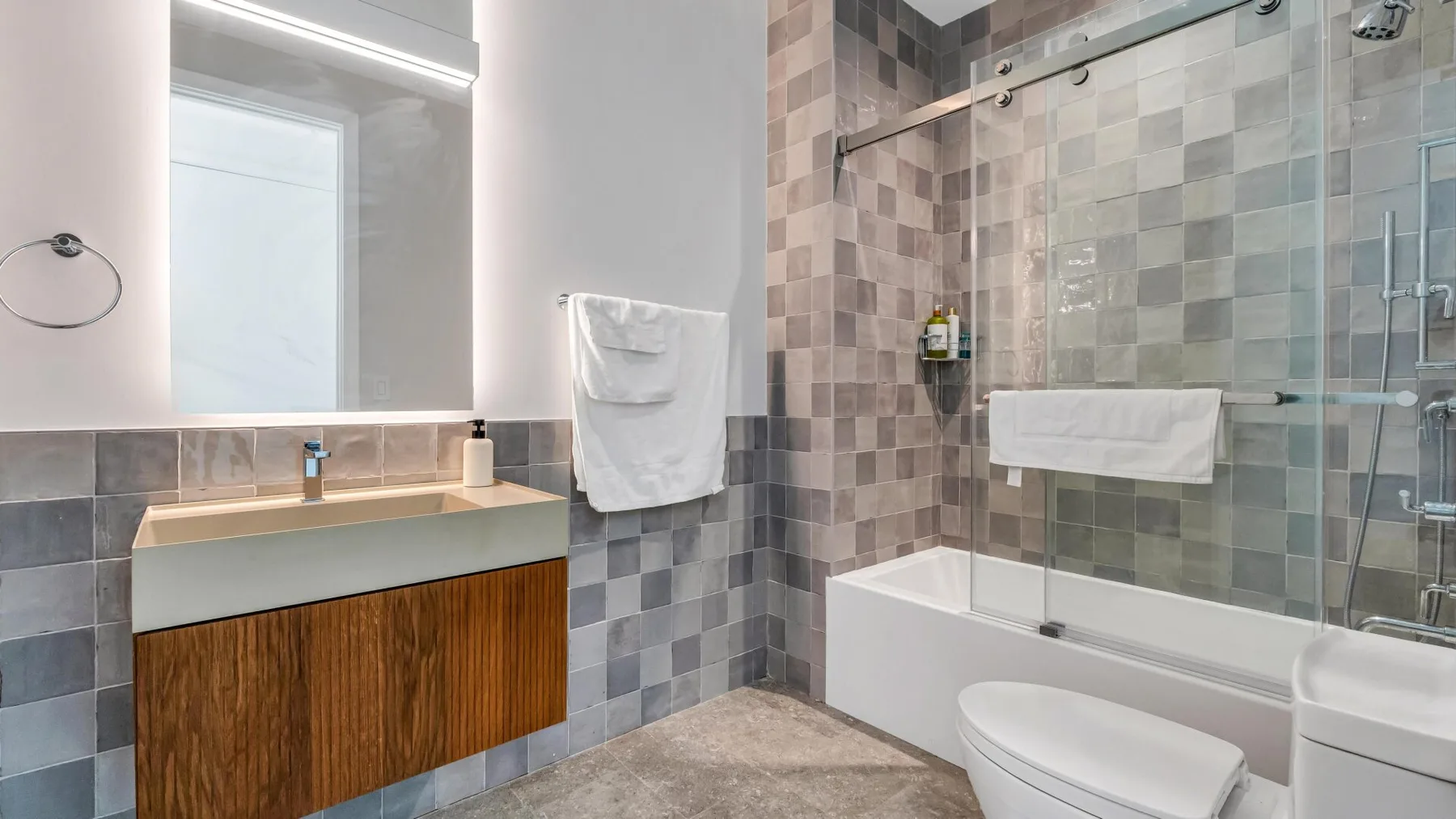 Un baño con azulejos, bañera, mampara de vidrio y lavabo.