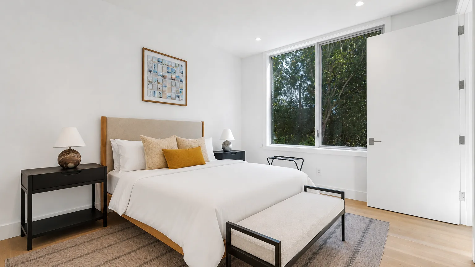 Un dormitorio luminoso con una cama tendida, mesitas de noche y una ventana amplia.