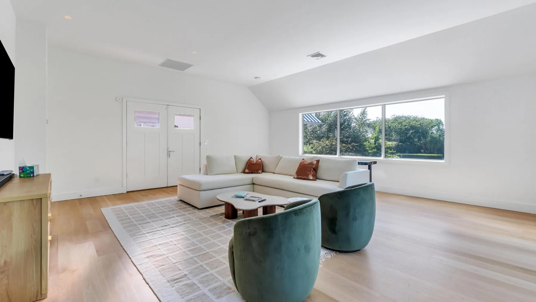 Una sala de estar luminosa con asientos seccionales y ventanas amplias.