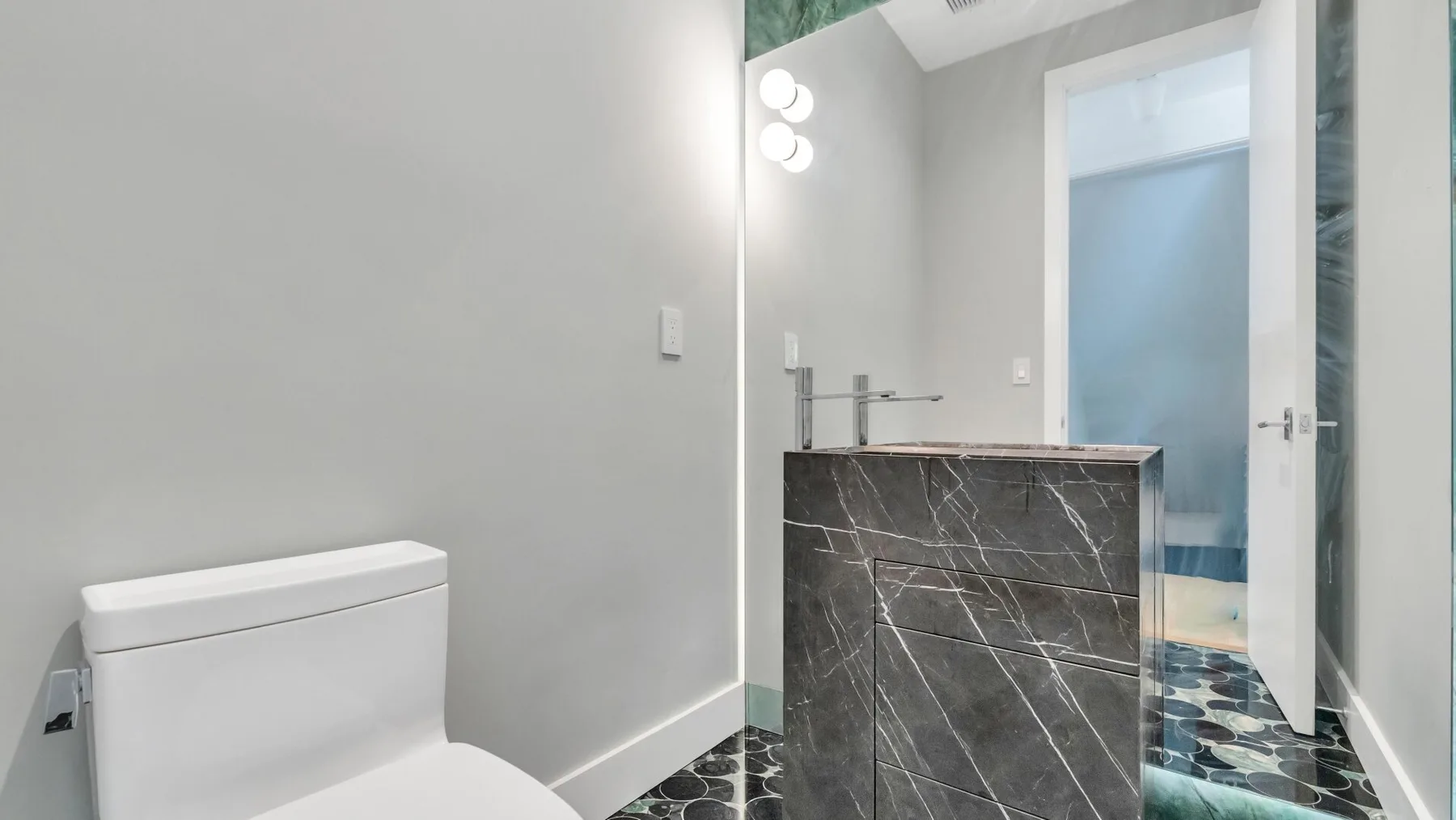 Un baño moderno con un tocador oscuro junto a un inodoro blanco.