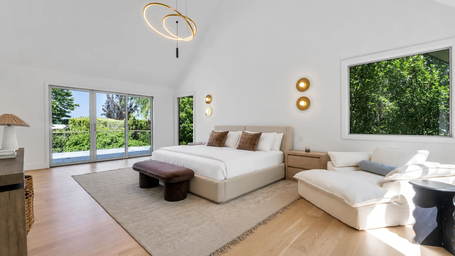 Un dormitorio luminoso con una cama grande y una zona de estar junto a amplias ventanas.