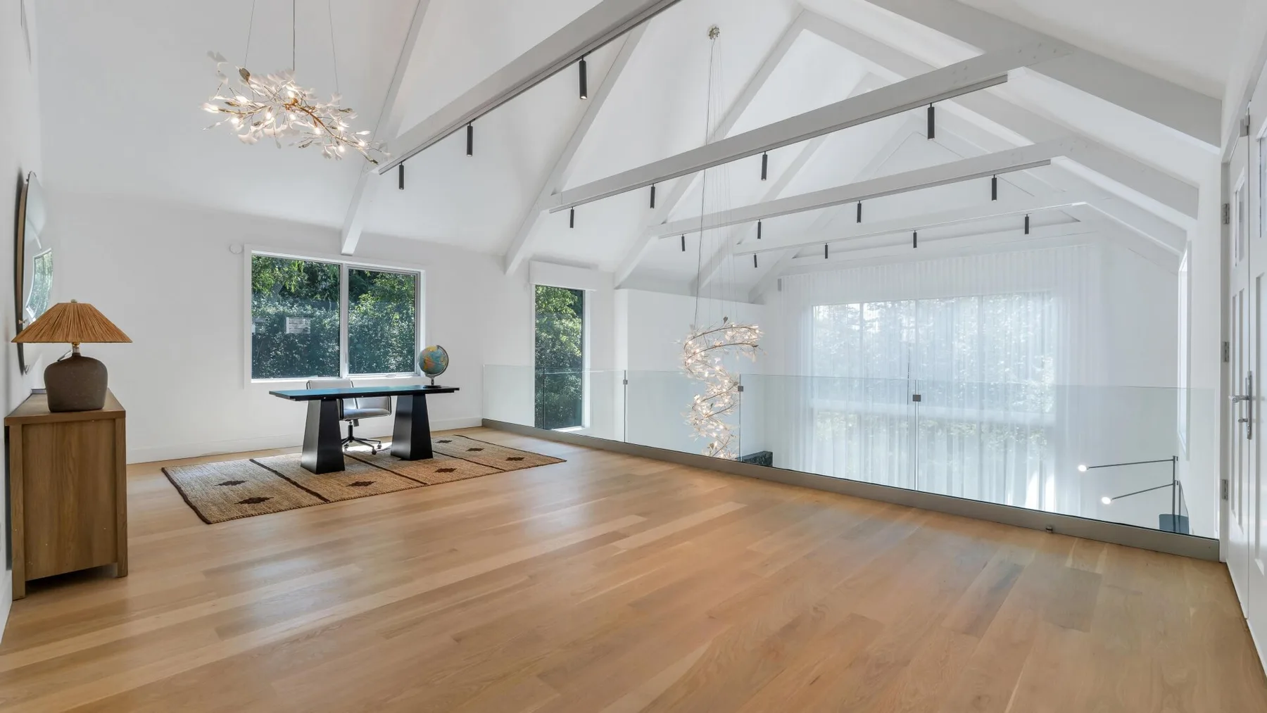 Interior diáfano y luminoso con suelo de madera y grandes ventanas.