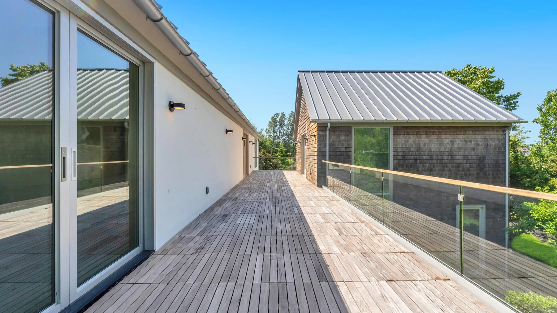 Una terraza exterior conecta dos edificios modernos, con barandillas de vidrio en el borde.