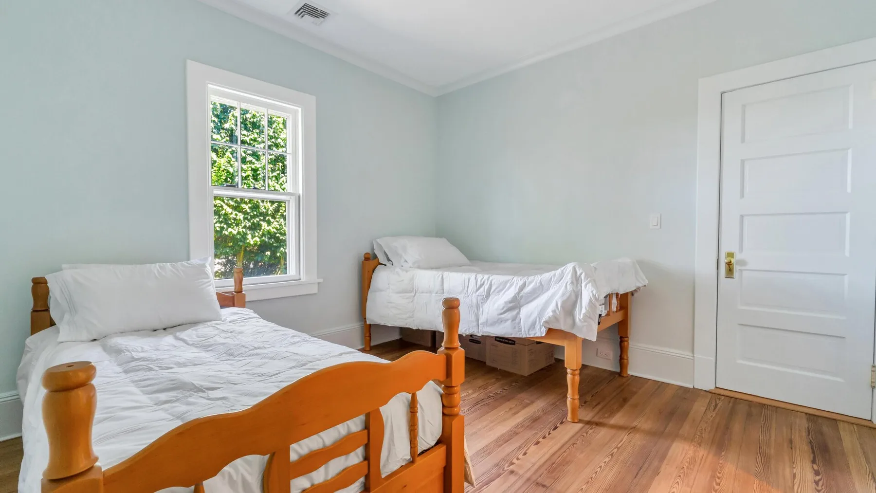 Un dormitorio con dos camas y una ventana con vistas a la vegetación.