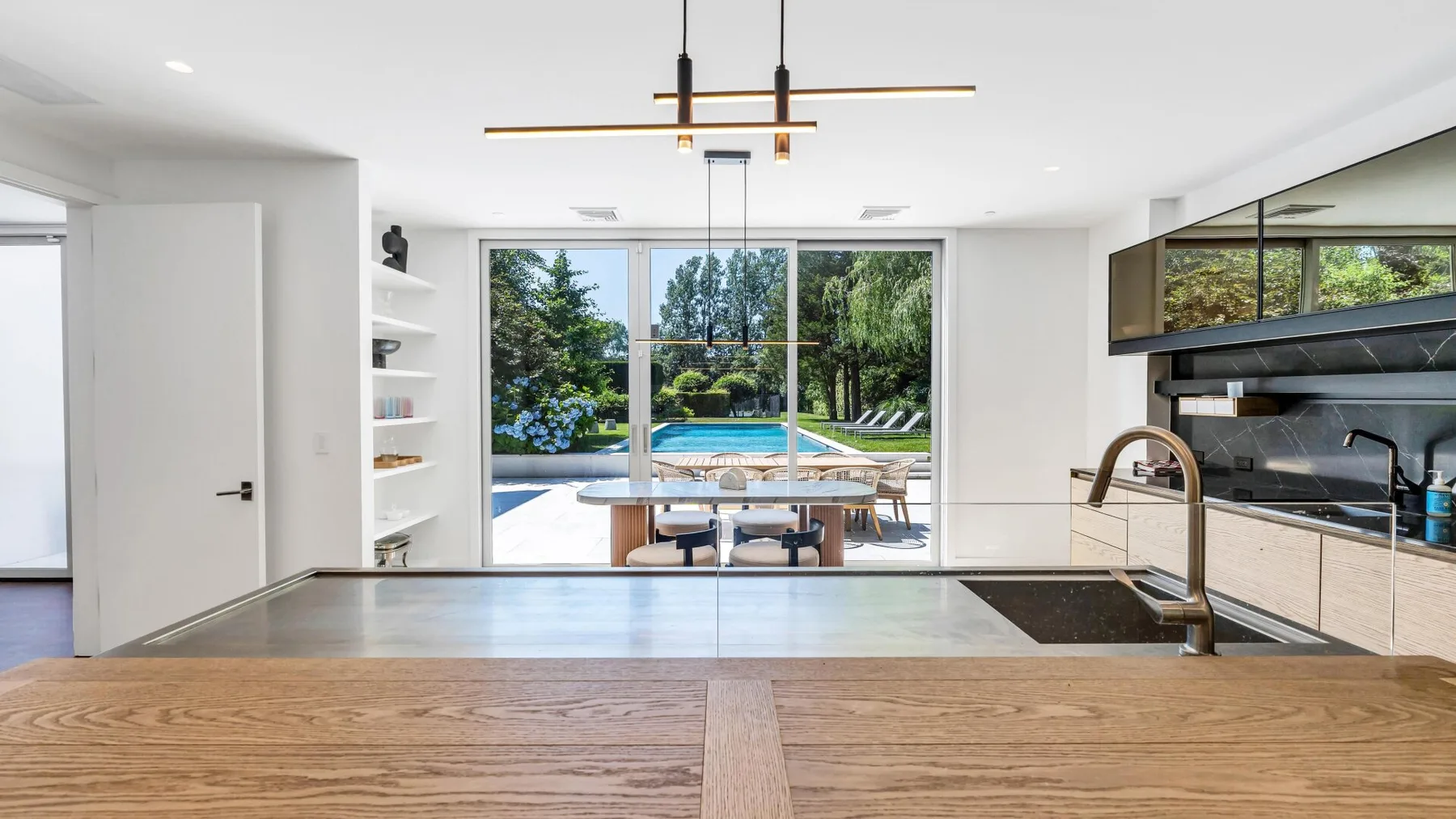Una cocina moderna se abre a un comedor y un jardín junto a la piscina.