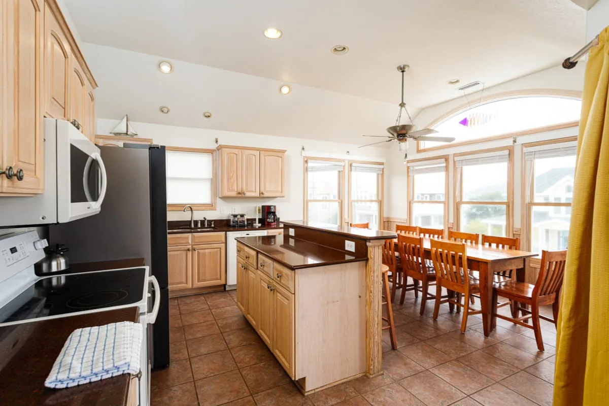 Cocina y comedor con una isla central y una mesa de comedor de madera.
