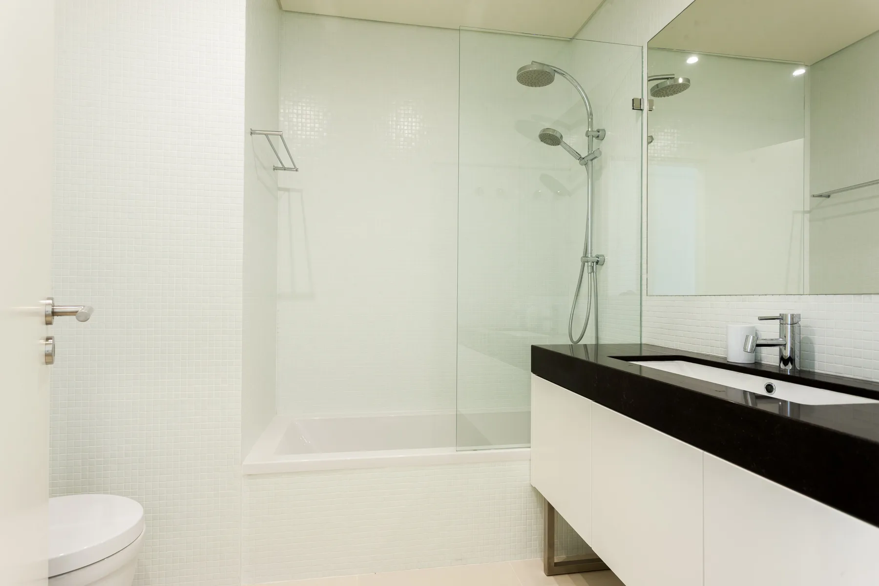 Un baño luminoso con ducha de vidrio y lavabo.