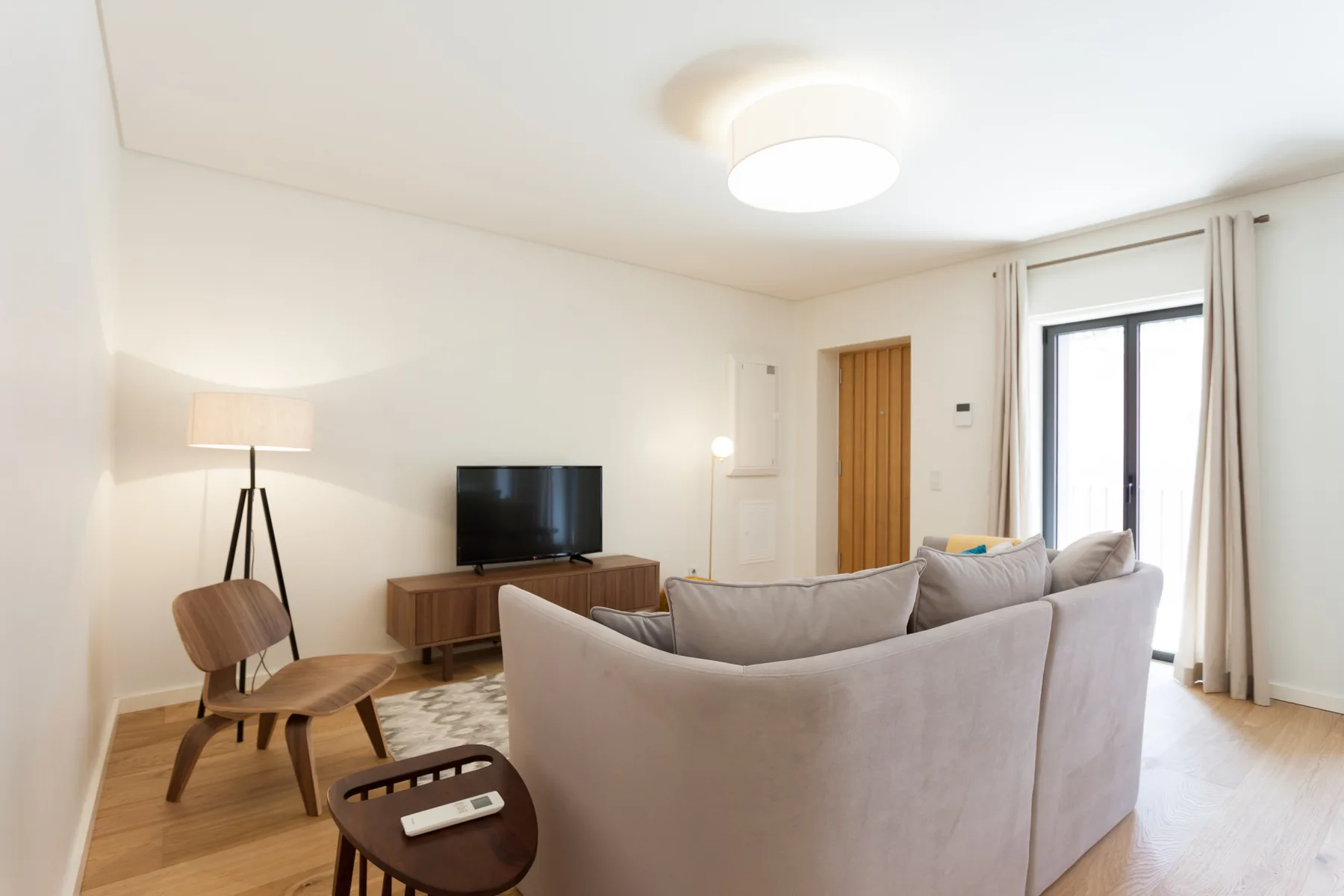 Una sala de estar luminosa con asientos, un televisor y una ventana alta.