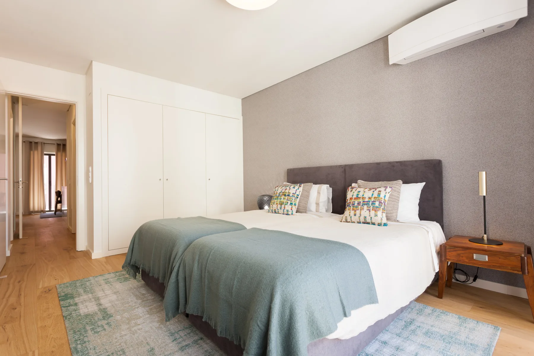 Un dormitorio con una cama doble, cojines estampados y un armario.