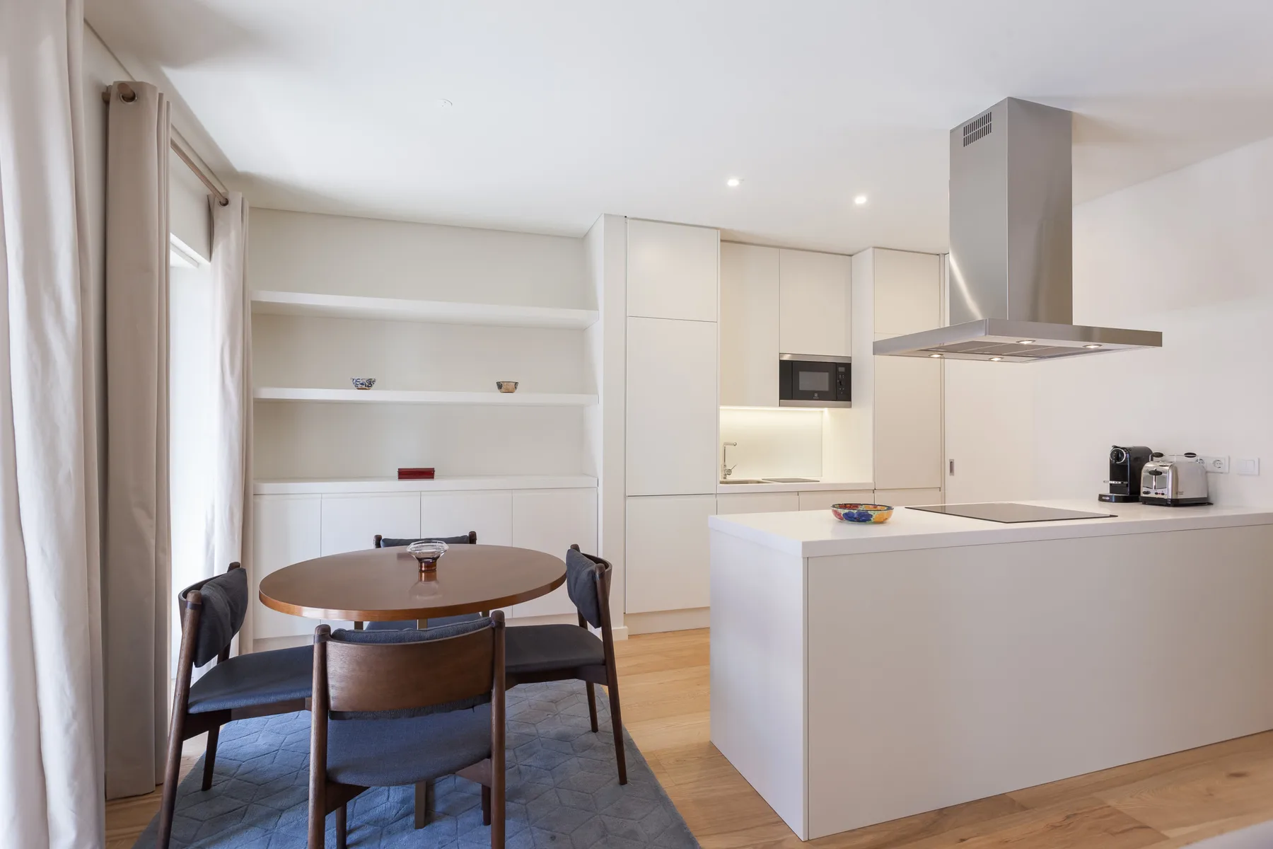 Comedor junto a una cocina moderna con armarios blancos e isla central.