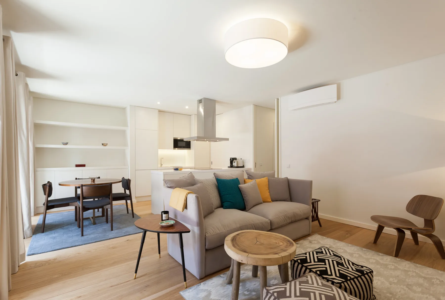 Una sala luminosa con asientos, una mesa de comedor y una cocina abierta.