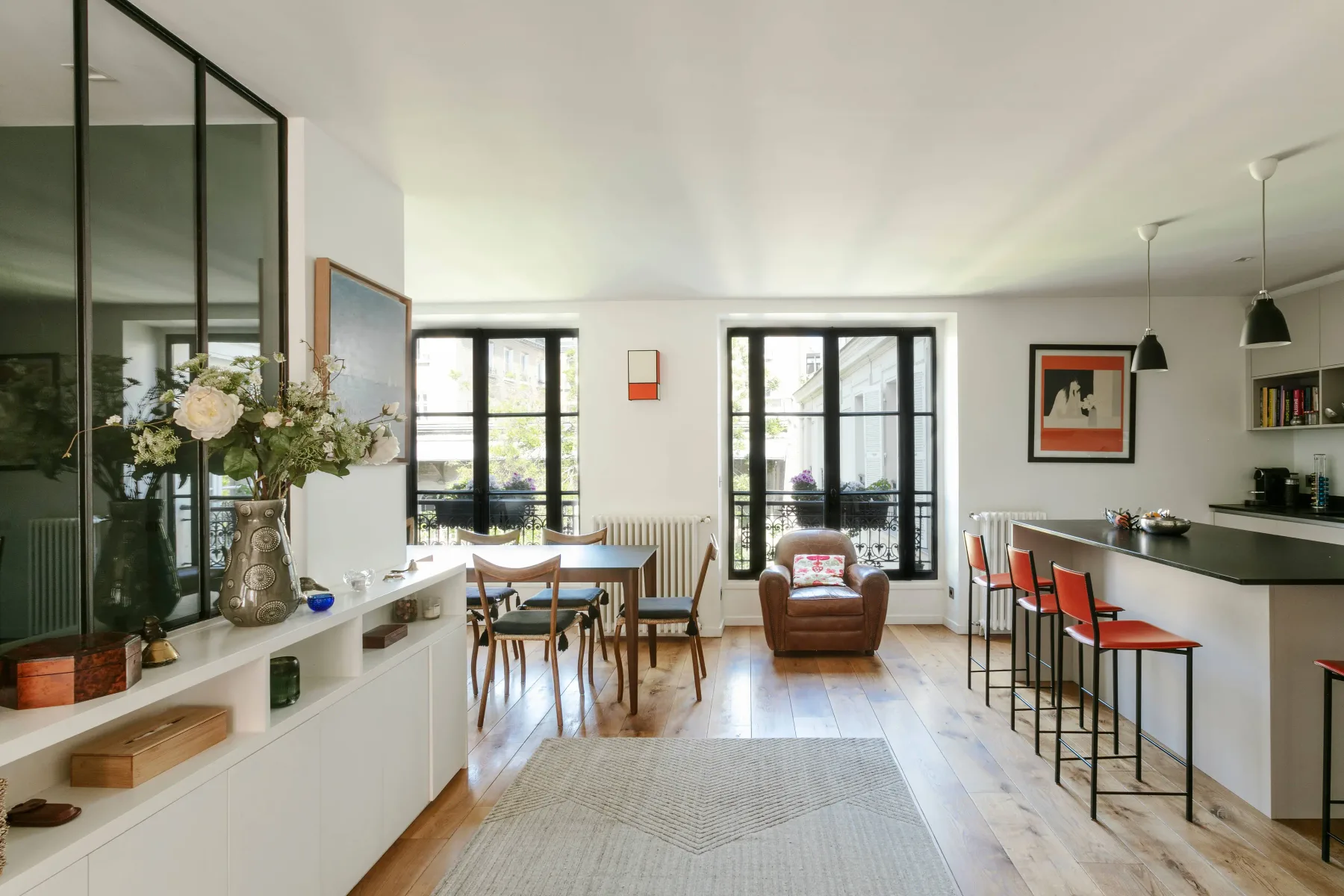 Una luminosa sala-comedor diáfana con grandes ventanas y una barra de cocina.