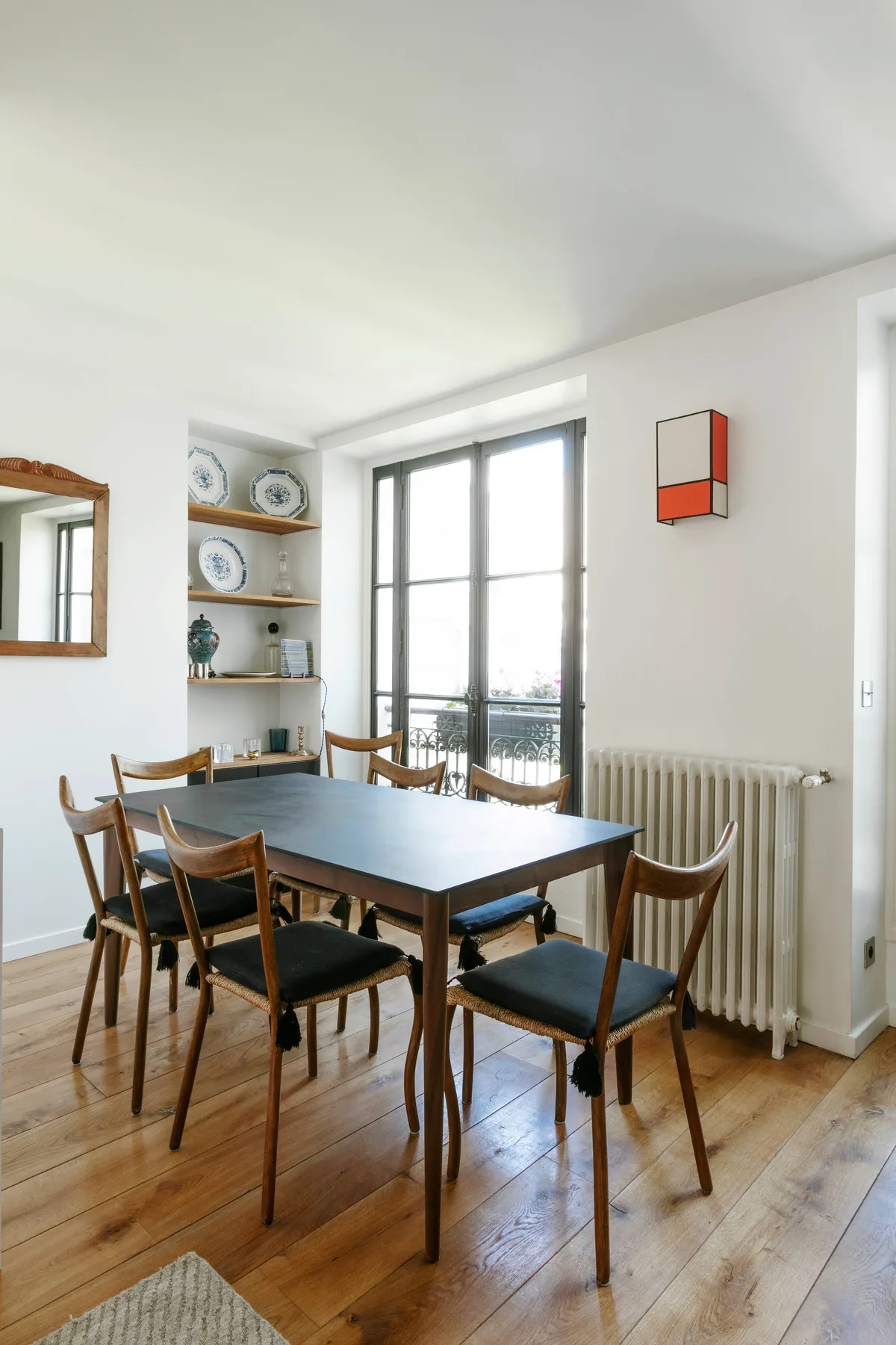 Un comedor luminoso con una mesa de madera y grandes ventanas.