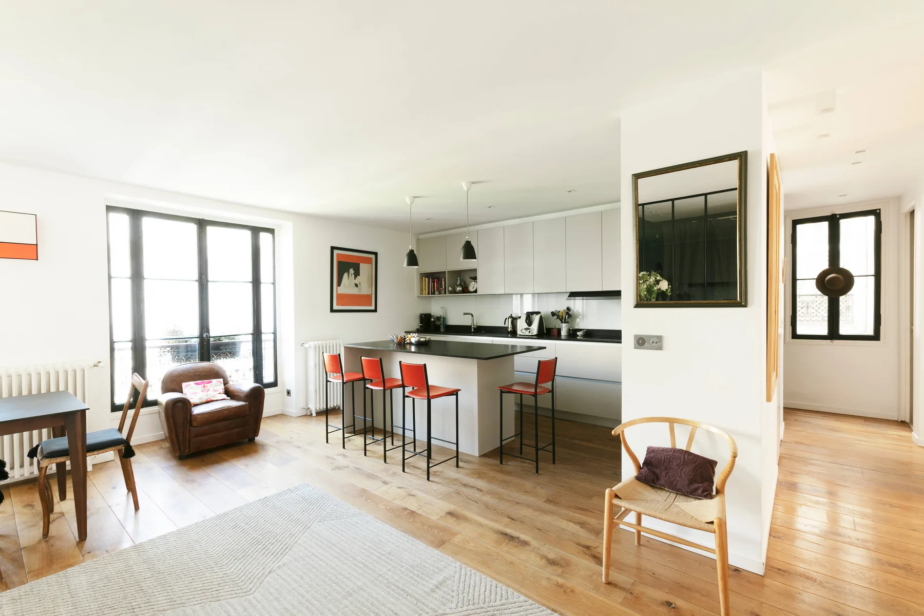 Una luminosa zona abierta de estar y comedor con una isla de cocina y asientos.
