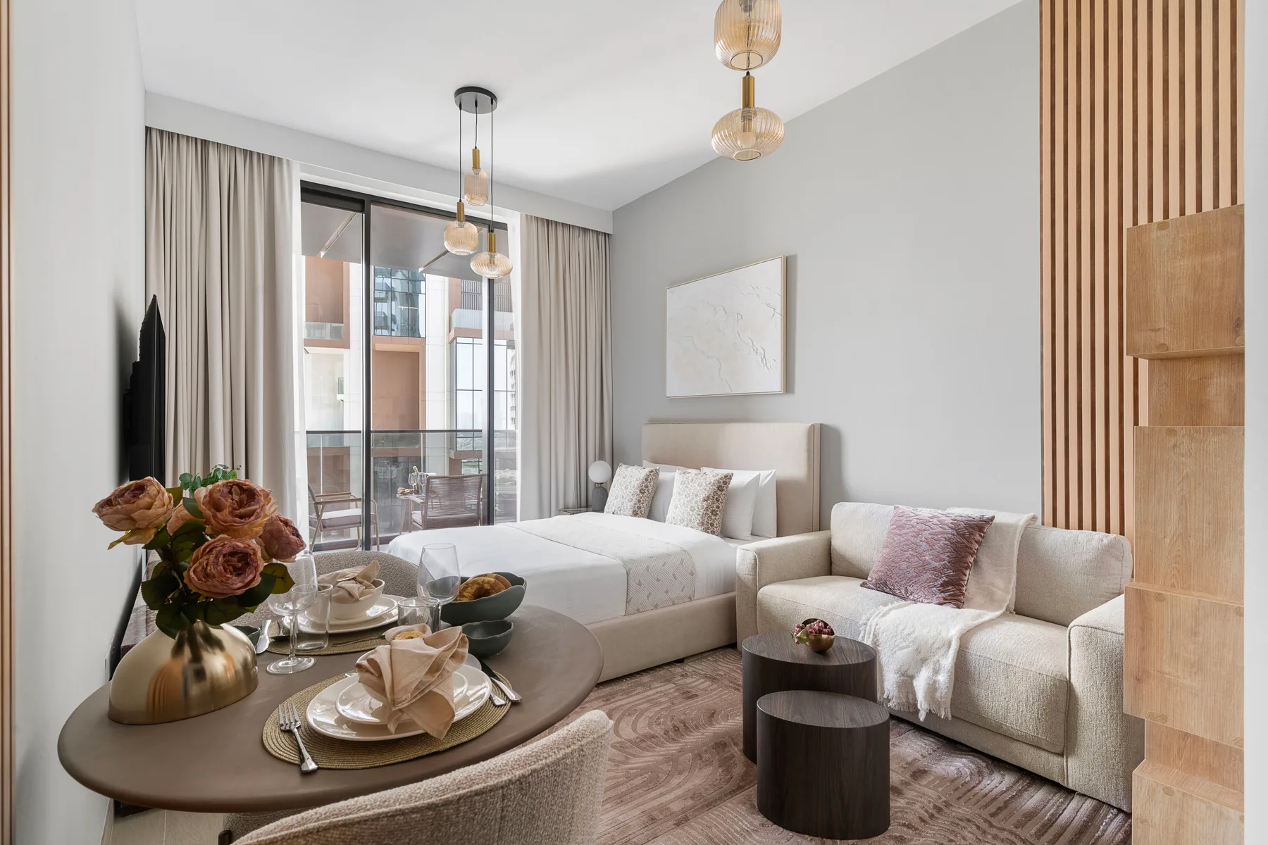 Una habitación de estilo estudio con una cama y una zona de estar junto a grandes ventanales.