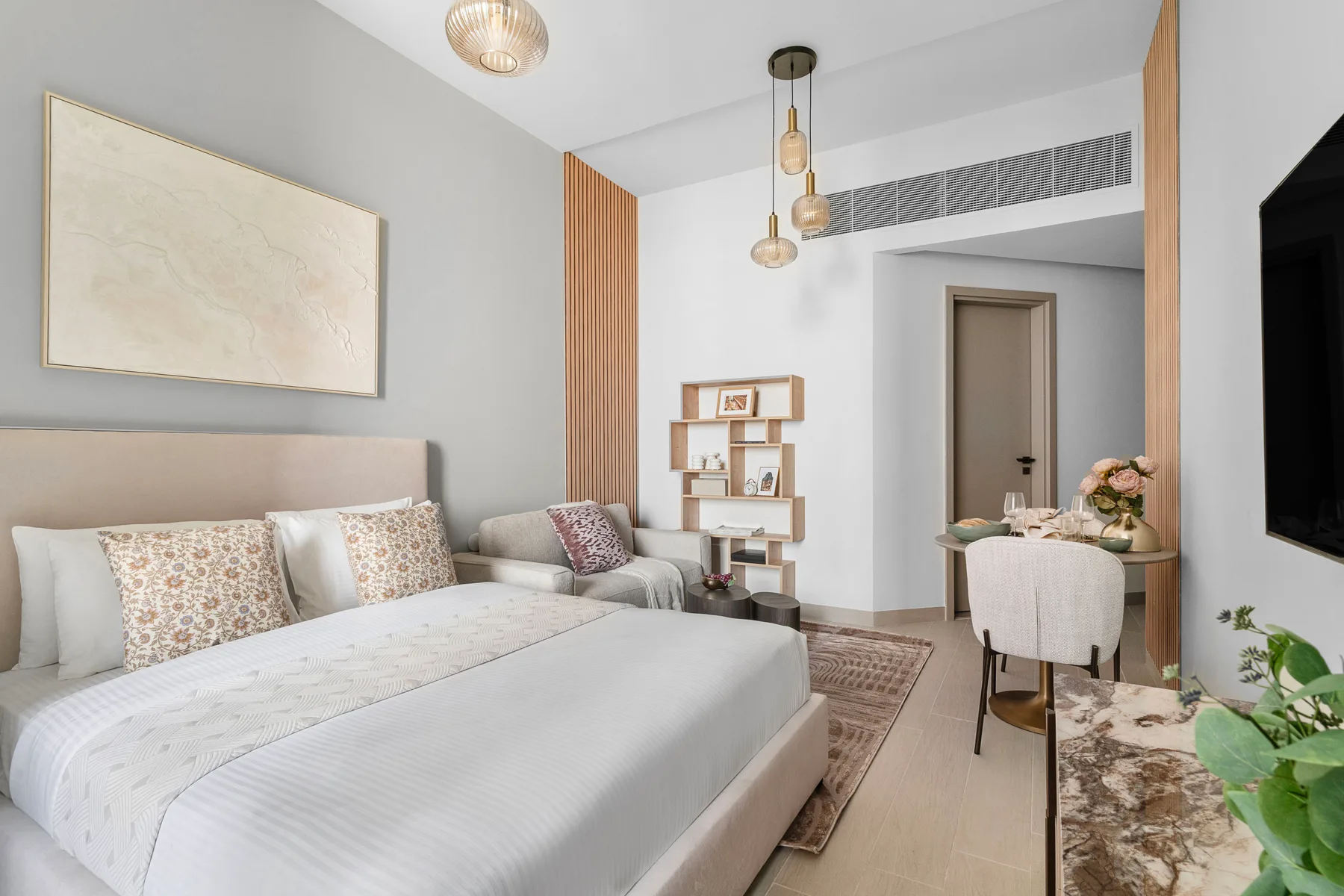 Un dormitorio luminoso con una cama grande, asientos y un pequeño escritorio.