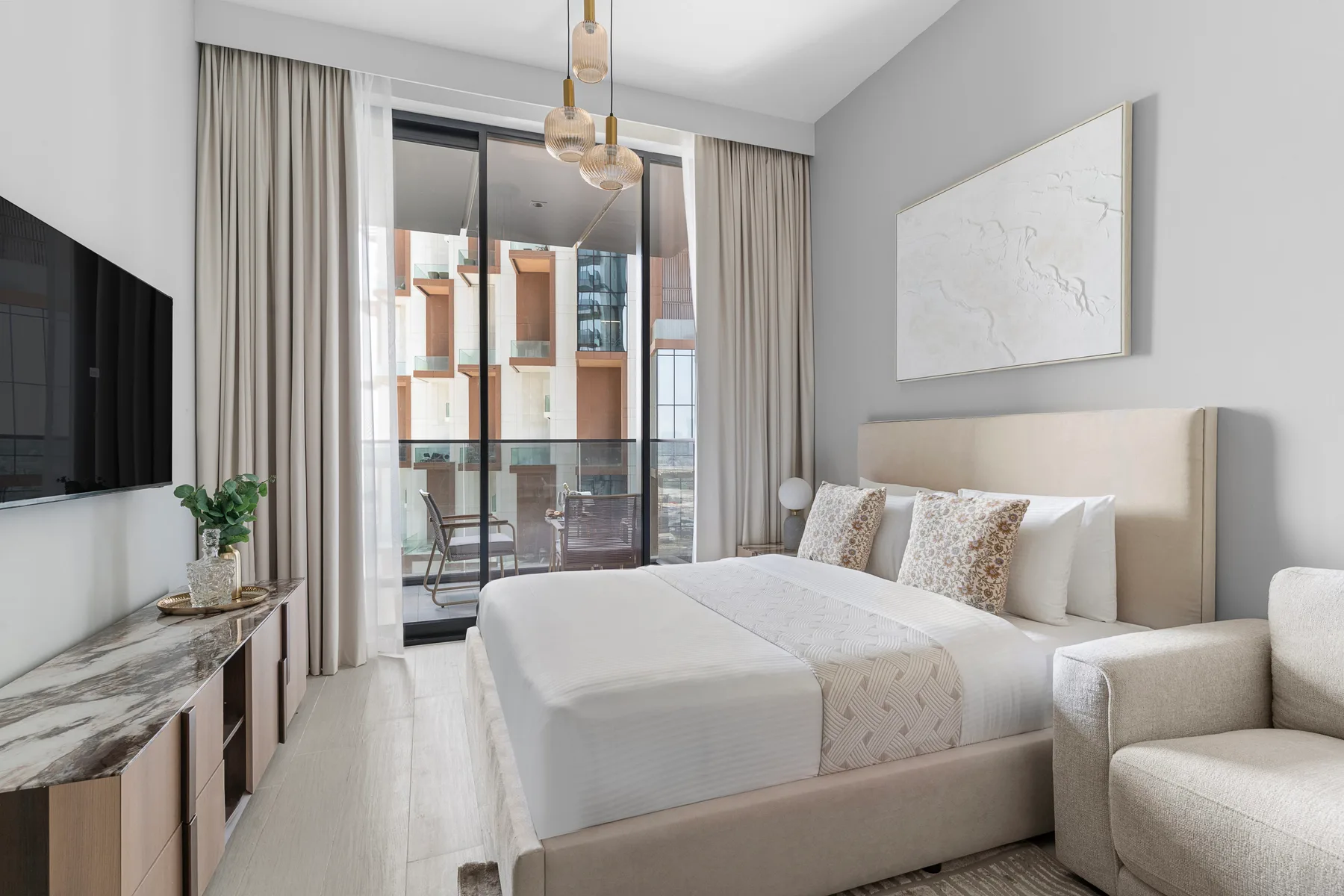 Un dormitorio luminoso con una cama tendida y puertas corredizas de vidrio.