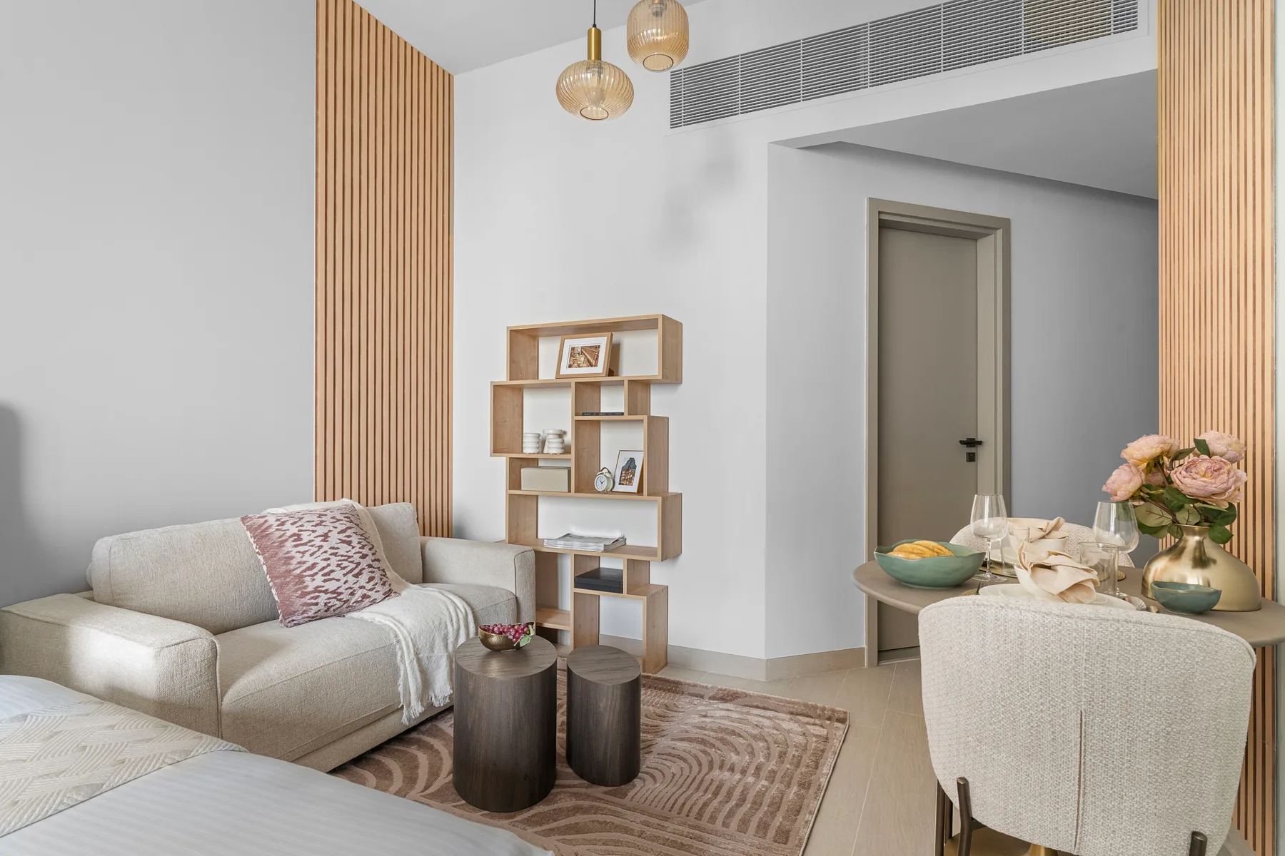 Una luminosa sala de estar y comedor con asientos, una estantería y una mesa puesta.