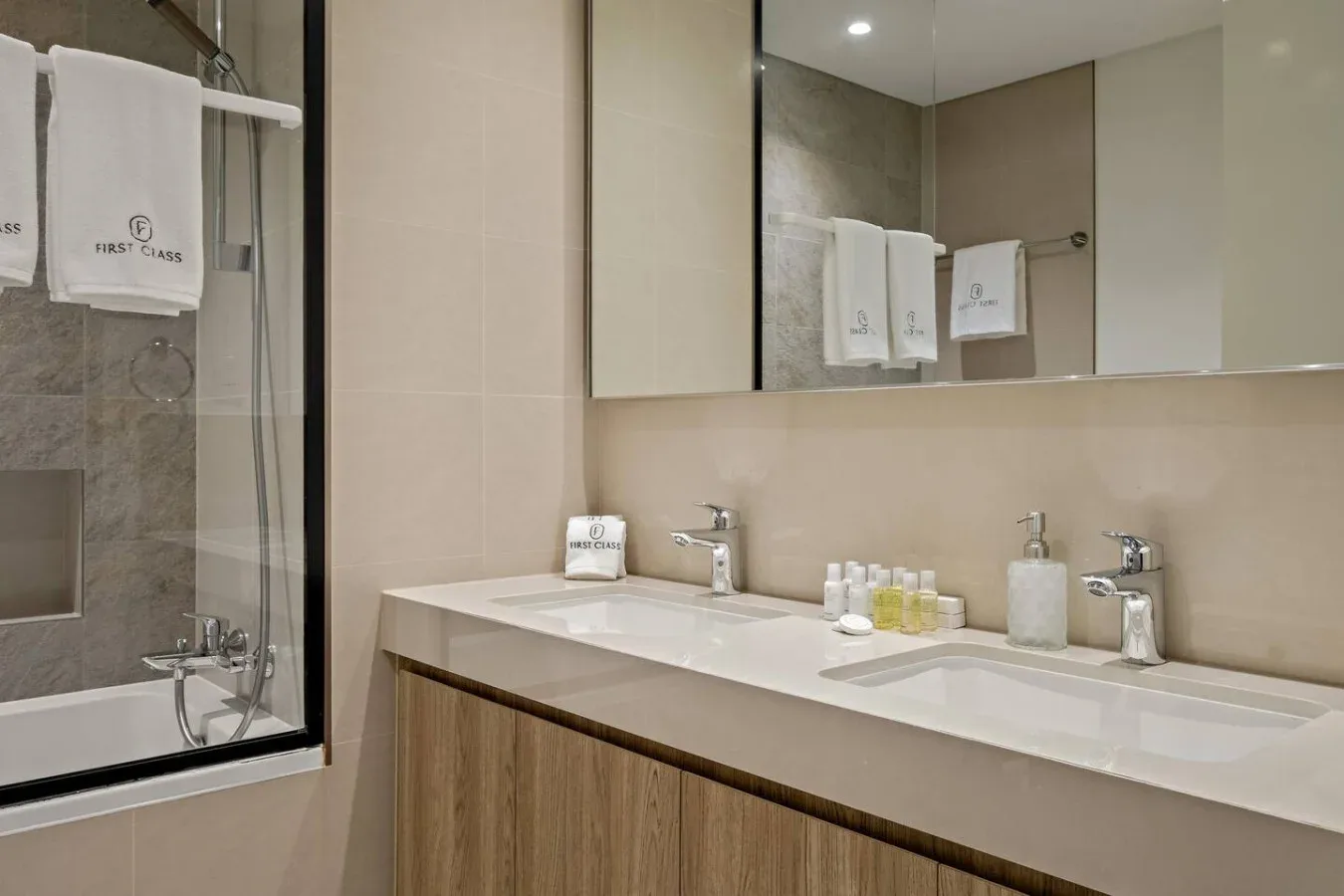 Un lavabo amplio de baño está junto a una ducha con panel de vidrio.
